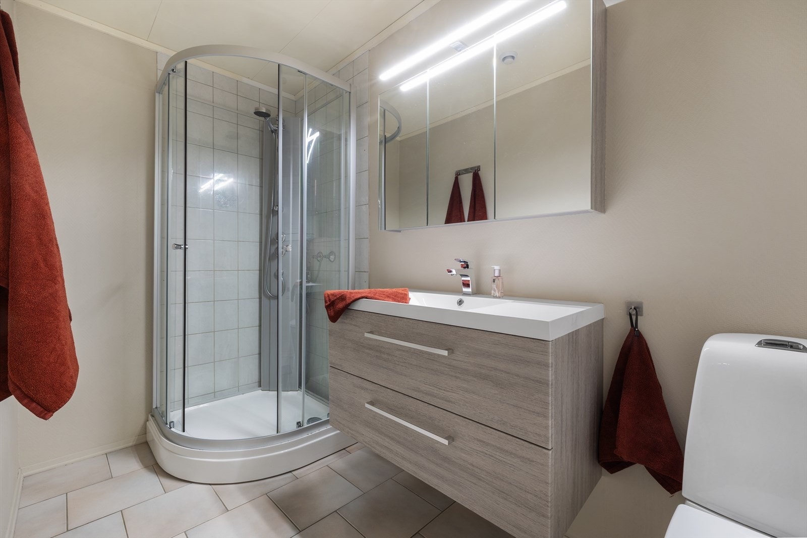 Badet i første etasje er innredet med dusjkabinett, servant, møbler og veggmontert wc. Galleribilde