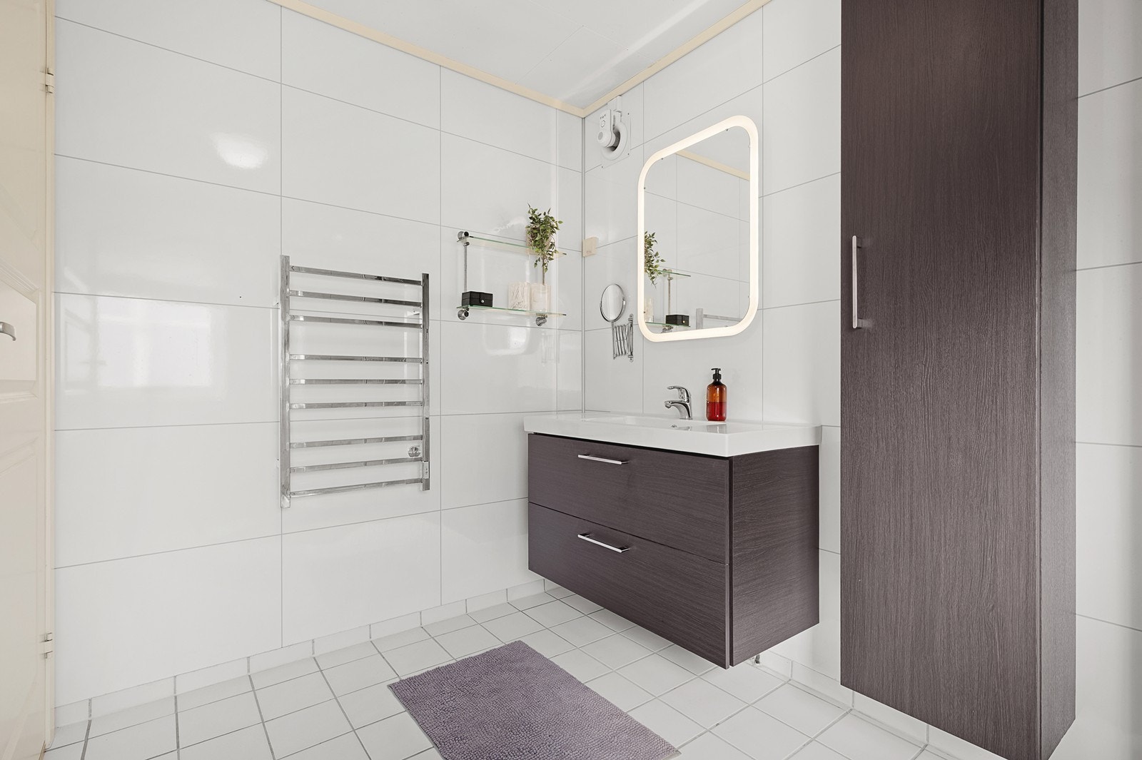 Rommet har flislagt gulv med varmekabler, og inneholder dusjkabinett, vegghengt toalett, servant med under- og sideskap/skuff, samt opplegg for vaskemaskin og tørketrommel Galleribilde