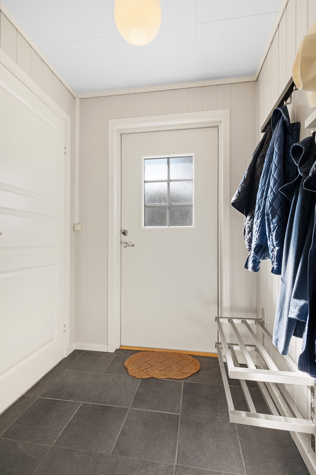 Du kommer først inn i et lysmalt vindfang med flislagt gulv. Herfra er det inngang til bod, og videre inngang til en romslig hall/gang. Galleribilde