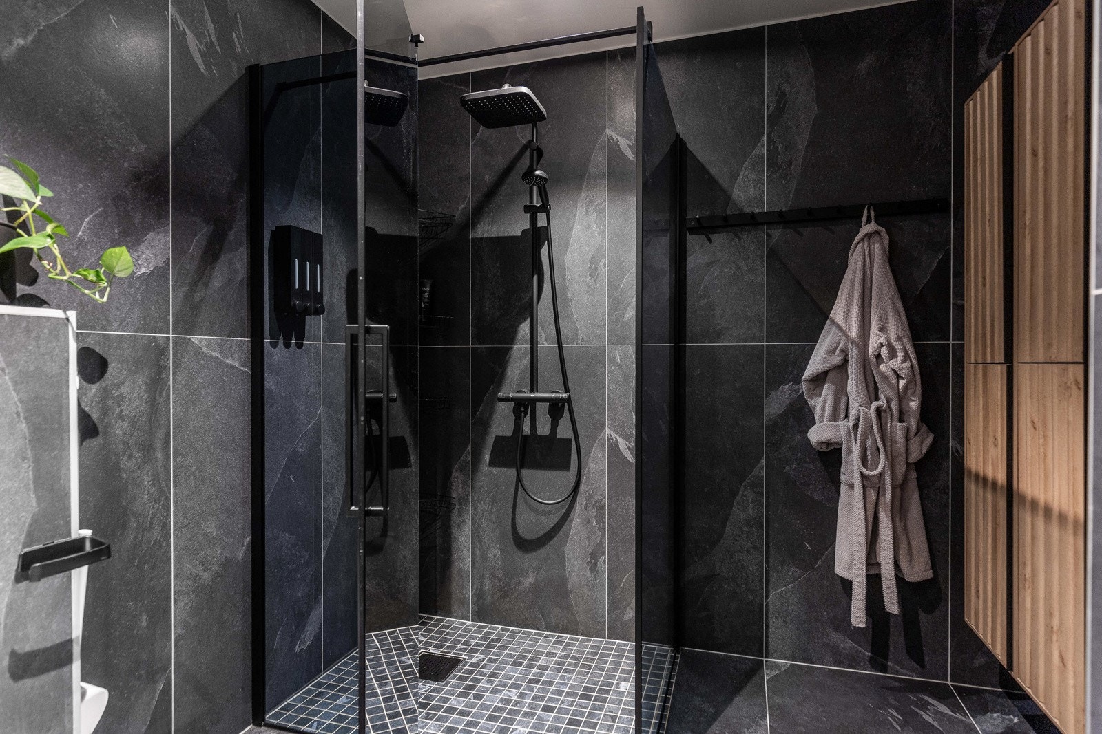 Badet har et stilig design og en moderne finish, med store, sorte vegg- og gulvfliser i marmormønster. Galleribilde