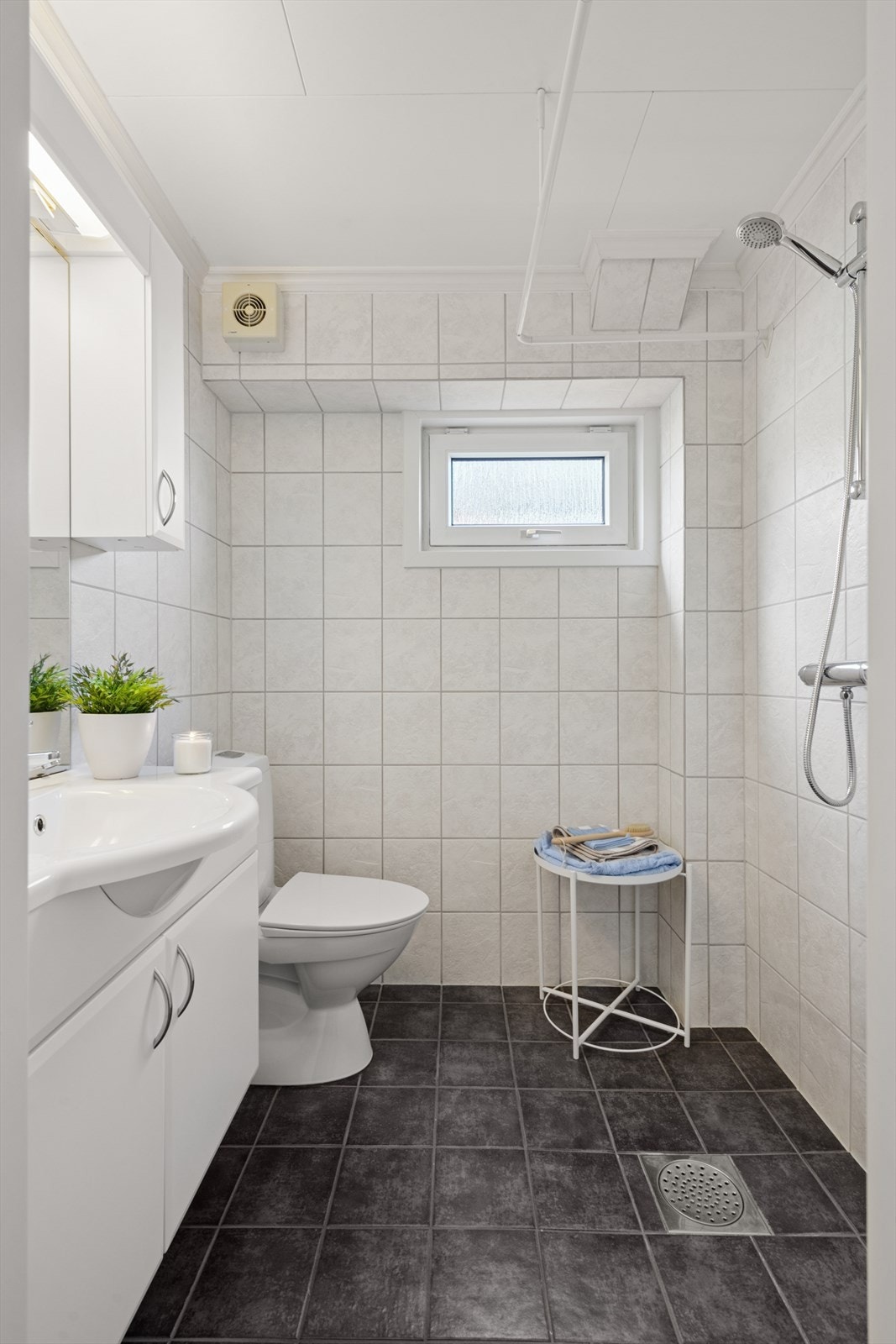 Badet har varme i gulvet, forheng i dusjsonen og et vindu for innslipp av naturlig lys. Mekanisk avtrekk. Galleribilde