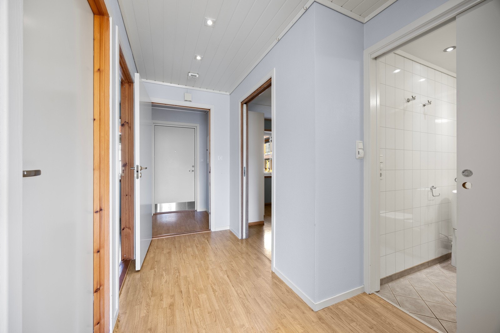 Inn til leilihgeten kommer du inn i en lys og åpen gang med god plass till oppbevaringmøblement Galleribilde