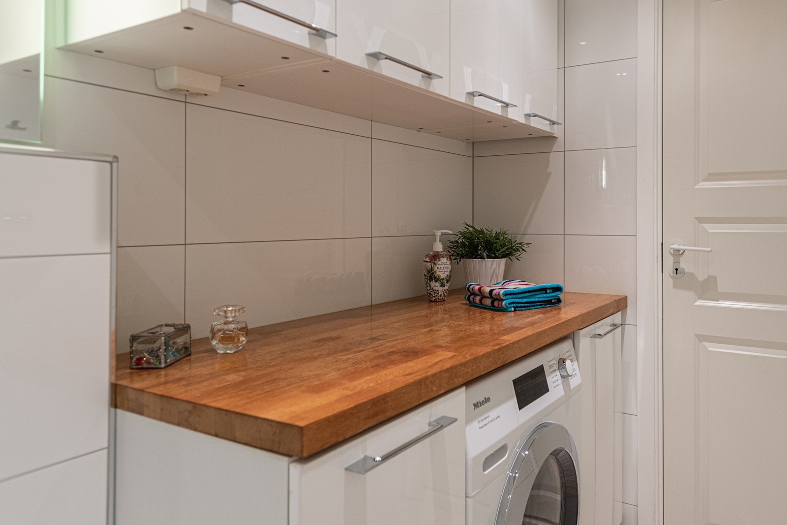 Praktisk løsning med benkeplate og mye skapplass over vaskemaskin Galleribilde