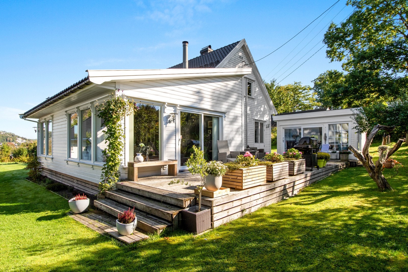 Fra stuen og kjøkkenet er det utgang til en sydvendt terrasse på ca. 57 kvm, med blomsterkasser og trapp ned til den flotte hagen. Galleribilde