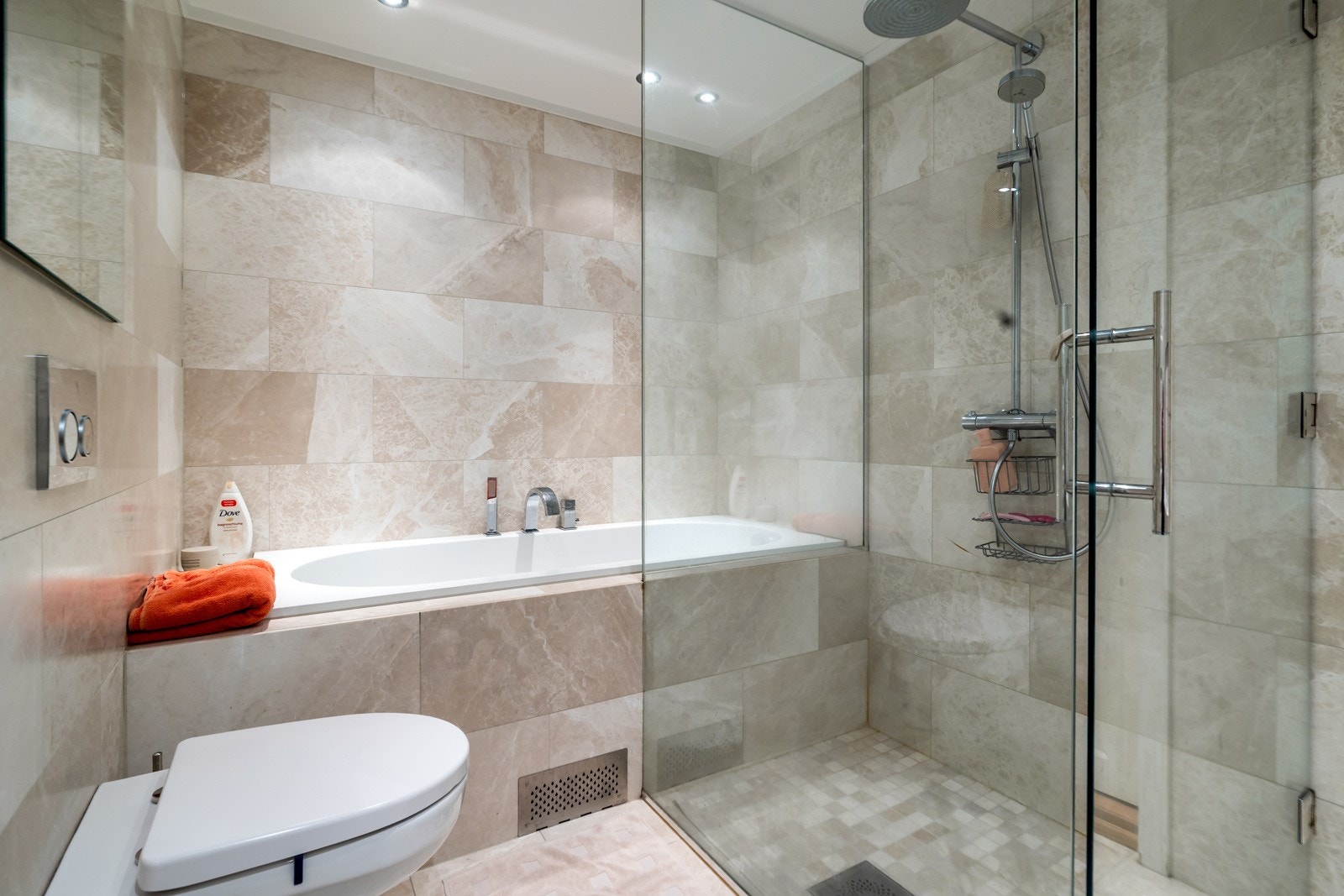 Badet er innredet med innredning, vegghengt toalett, dusjvegger og innbygget badekar. Galleribilde