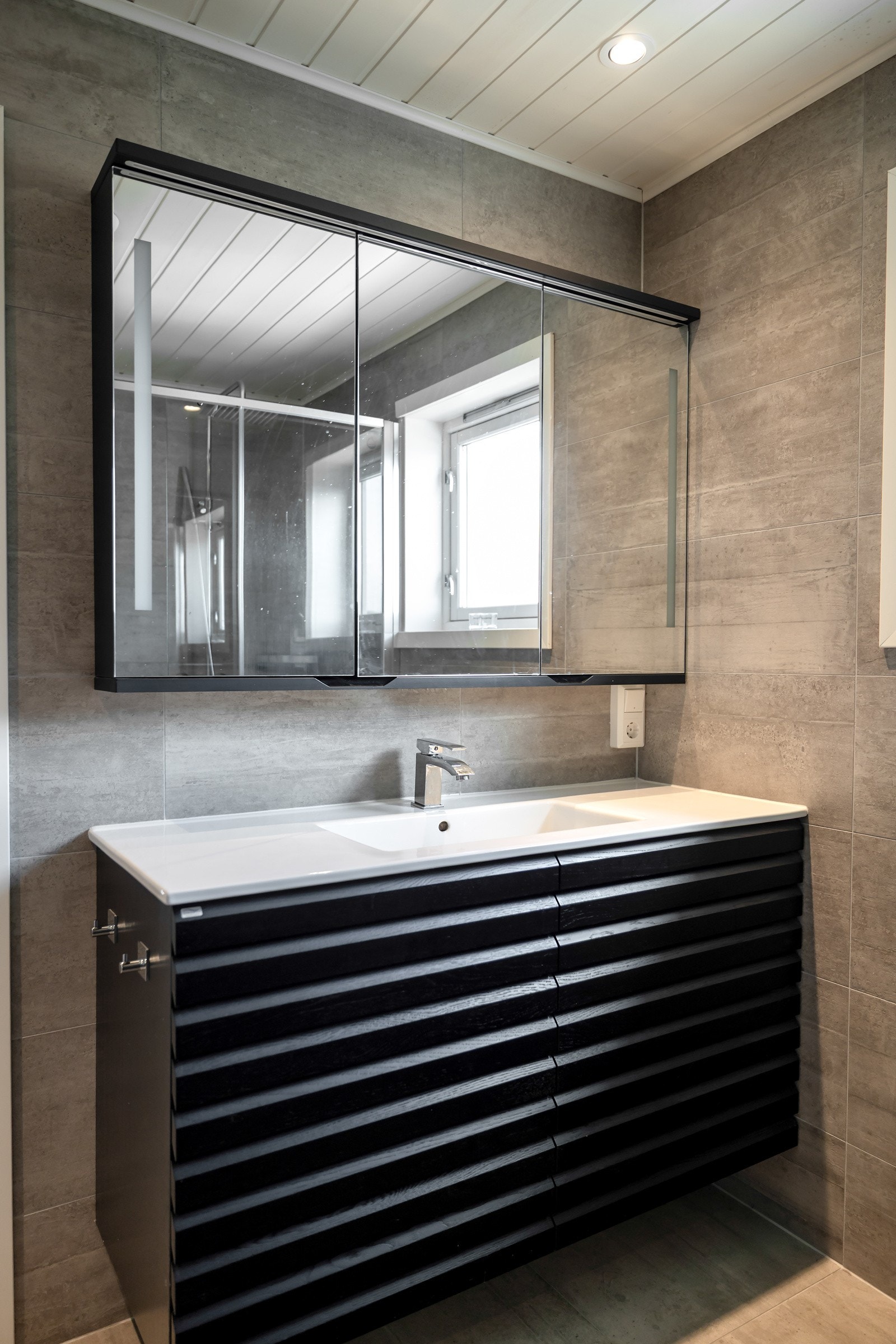 Badet ble oppgradert i 2020 med nye fliser og moderne innredning. Her finner du en helstøpt servantbenk med brede skuffer, speilskap, dusjvegger og vegghengt toalett. Det er varmekabler i gulvet. Galleribilde
