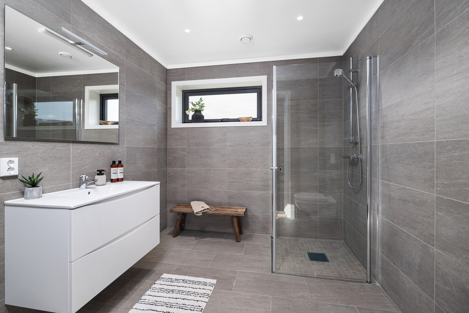 Badet i 1. etasje er delikat innredet med flislagte overflater, downlights og varme i gulv. Galleribilde