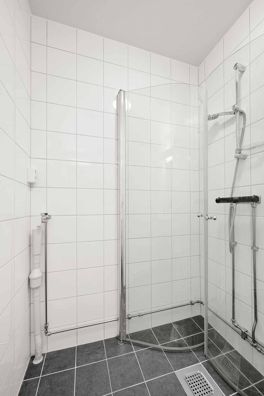 Badet inneholder innredning med vask og speil, toalett og dusjnisje med glassdører Galleribilde