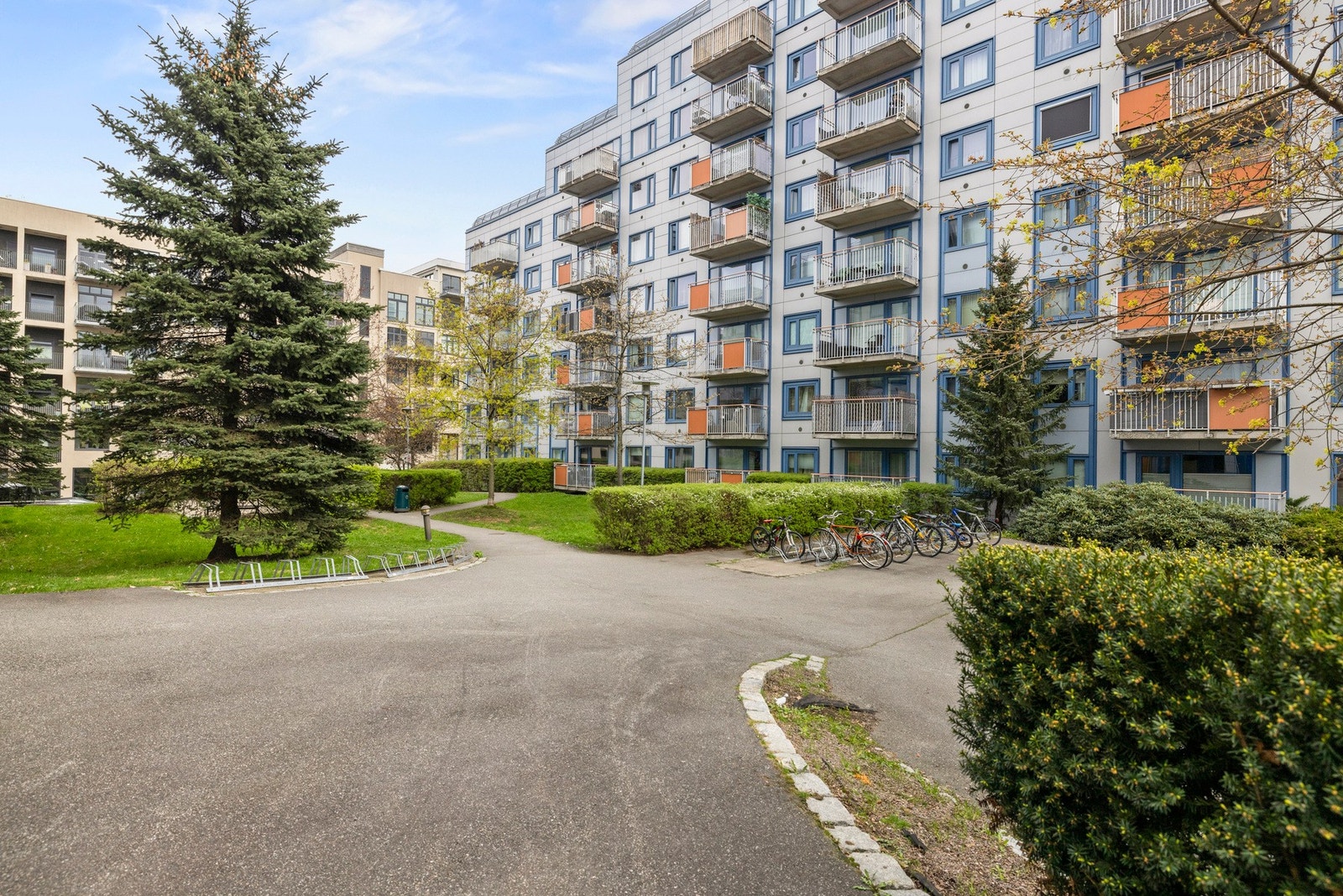 Byggets fasade er omkranset av natur og fellesareal Galleribilde