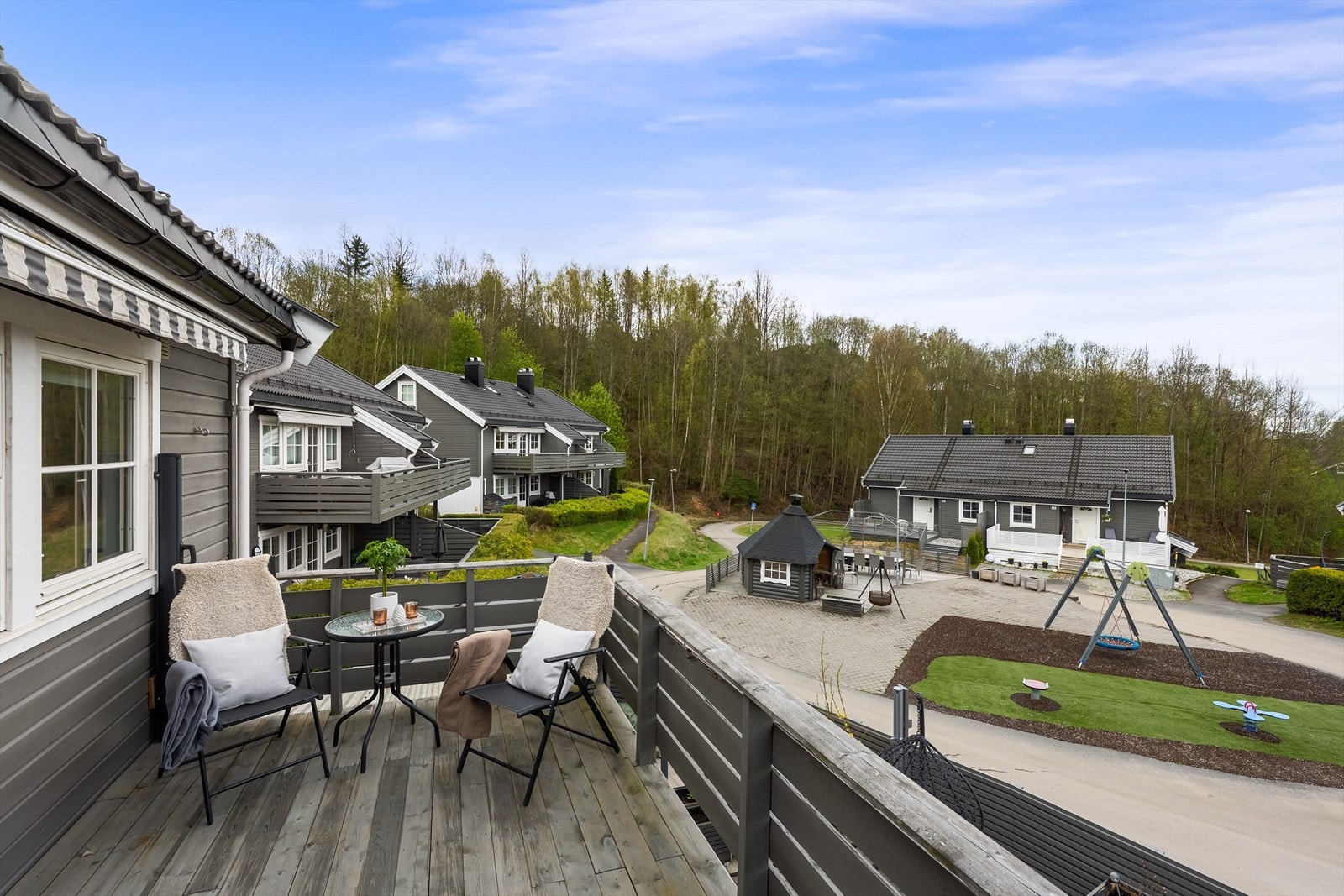 Fra balkongen er det hyggelig utsyn mot fellesområdene med lekeplass og grillhytte. Det er montert en uttrekkbar skillevegg på enden av balkongen. Galleribilde