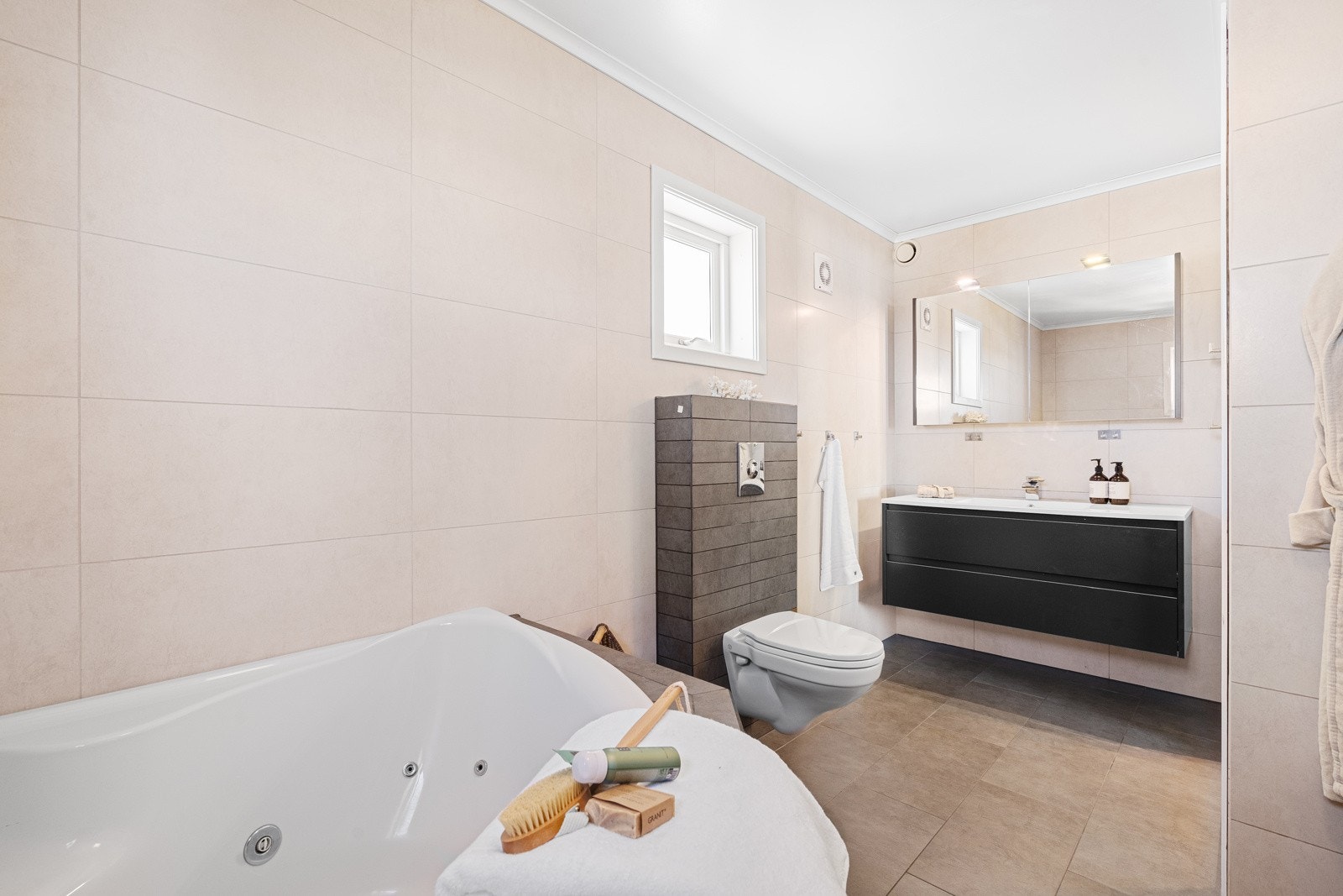 Badet inneholder både hjørnekar, dusj, vegghengt toalett og servant med innredning Galleribilde