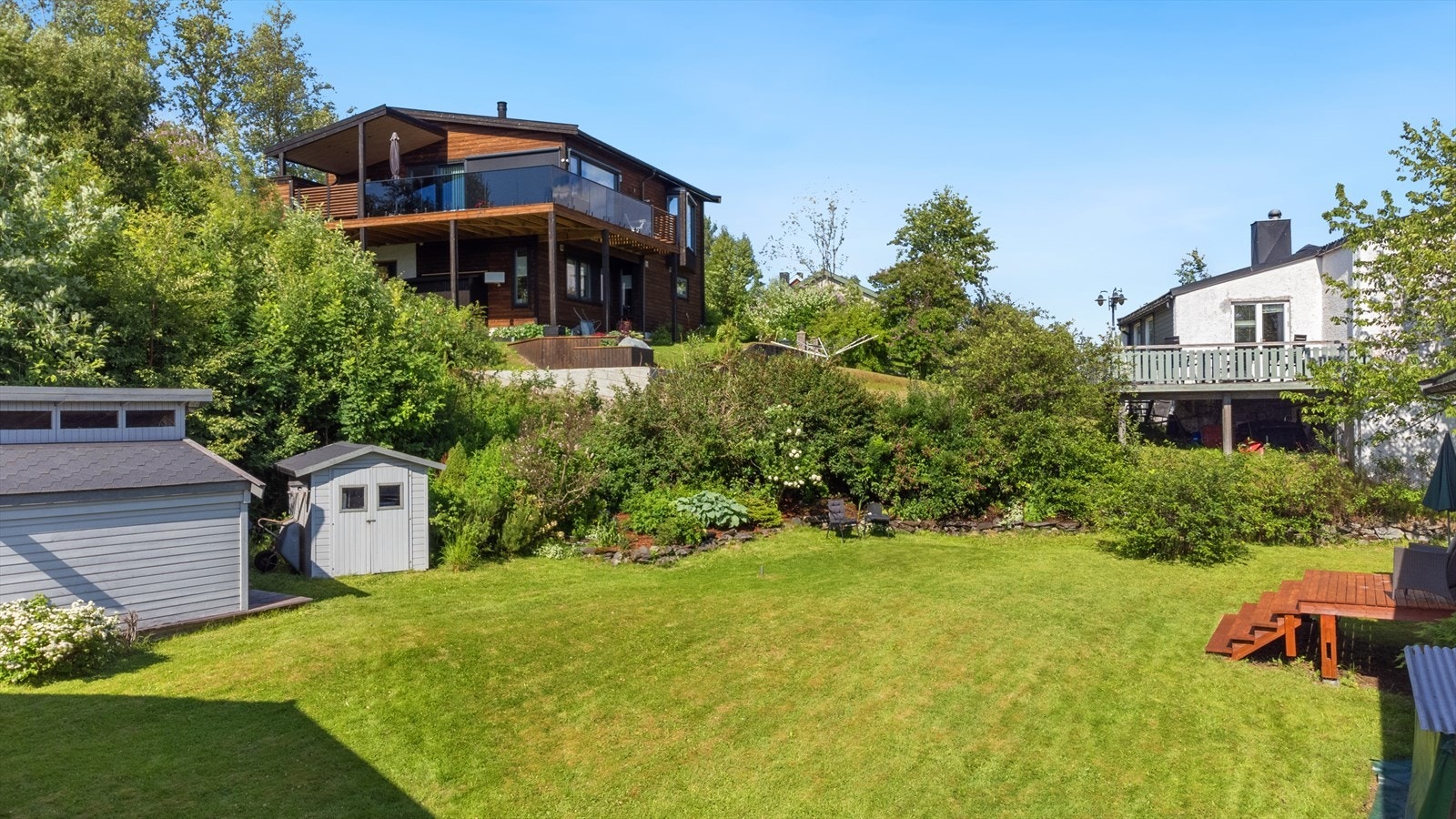 Frodig hageområde som om sommeren oppleves som en oase, med flotte prydbusker og beplantninger. Galleribilde