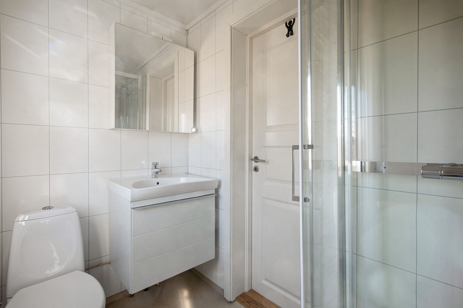 Pent, flislagt bad med varmekabler i gulv. WC, servant med skuffer under og dusjkabinett. Galleribilde