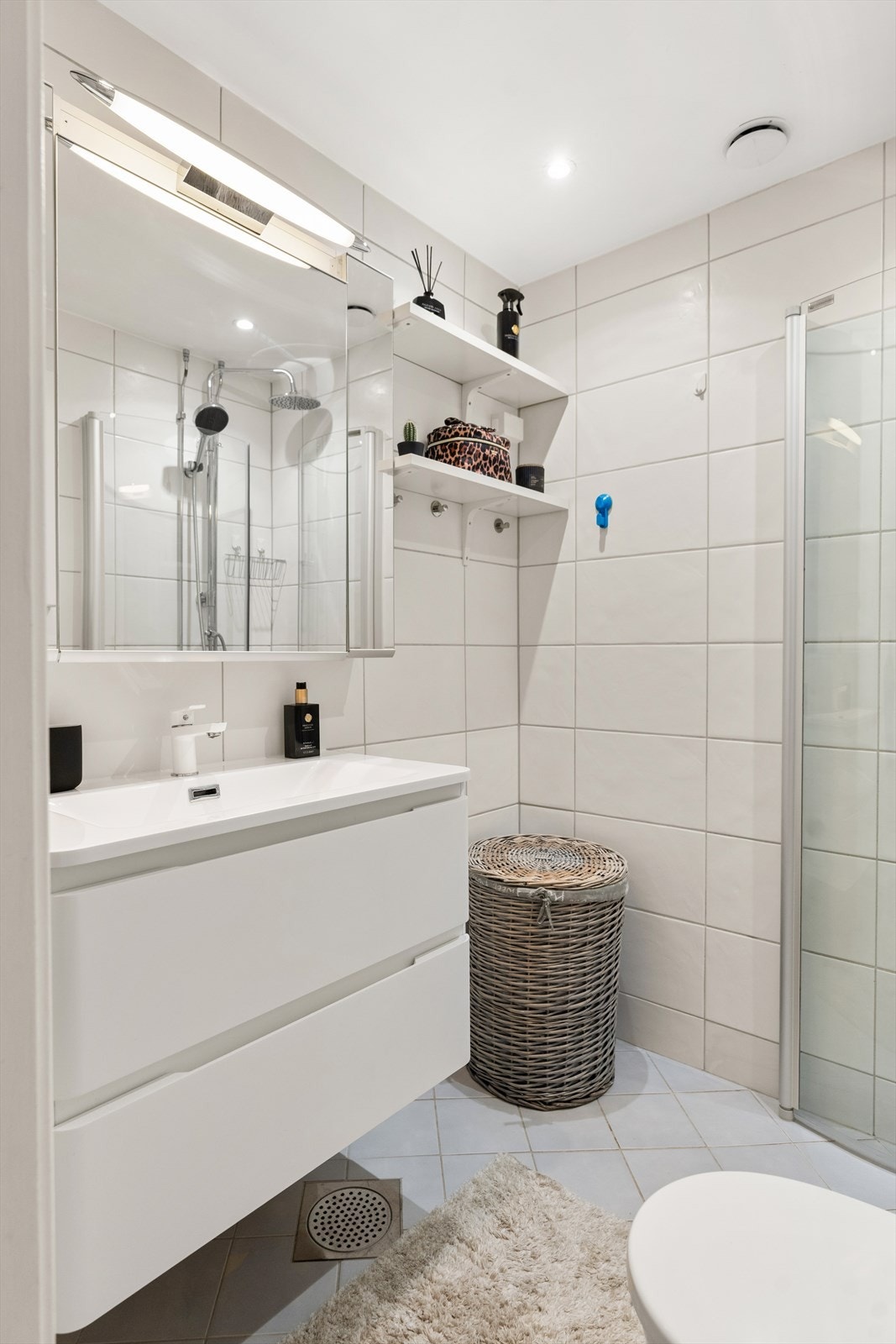 Badet inneholder speilinnredning med lys, toalett og dusj i hjørne bak svingbare glassvegger. Galleribilde