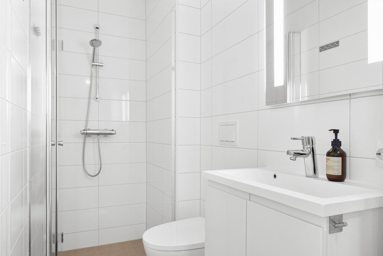 Badet har varme i gulvet og innredet med dusjnisje, vegghengt toalett, speil med int. belysning og servant i baderomsinnredning. Galleribilde