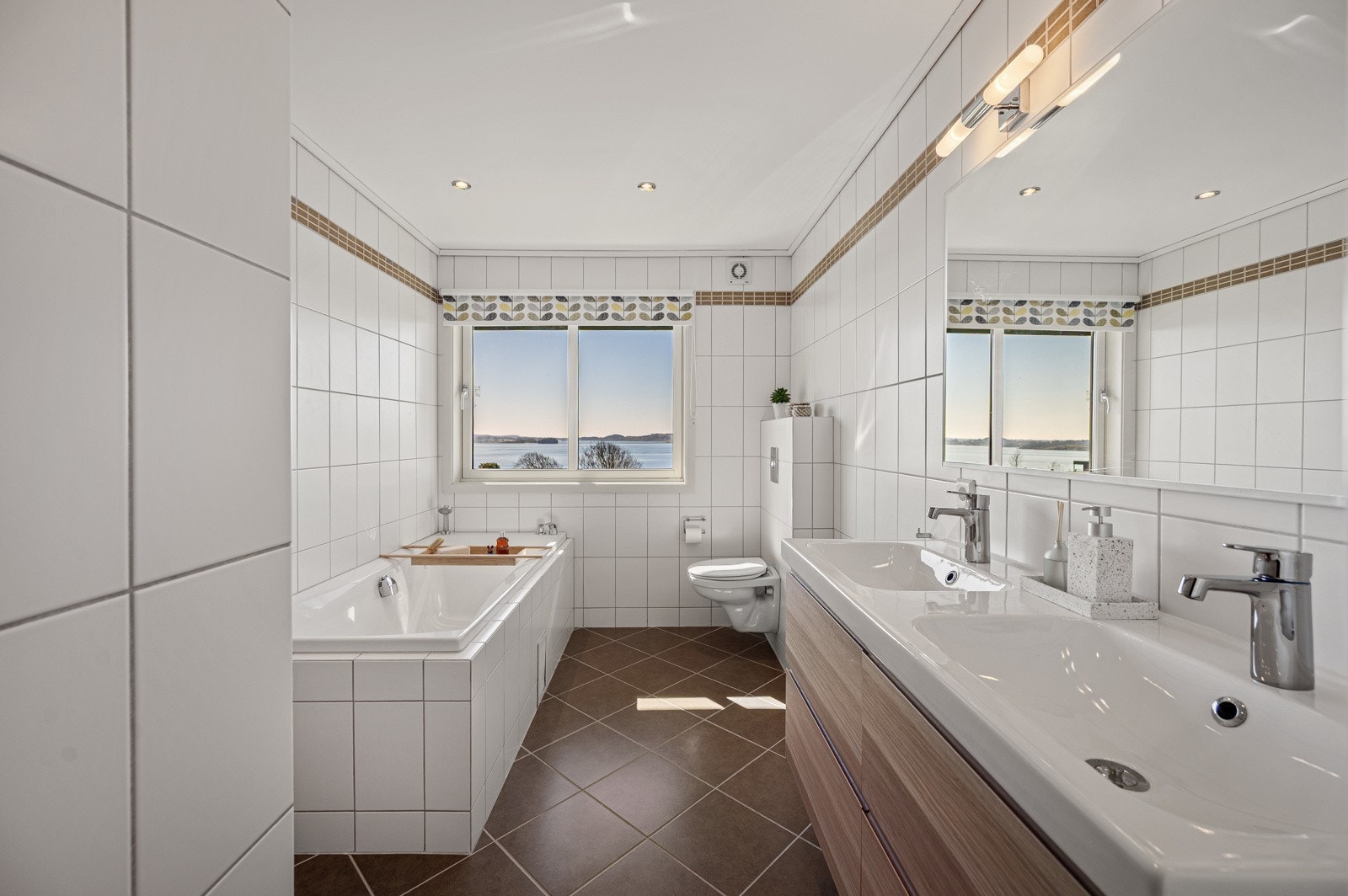 Stilrent helfliset bad med dobbel servant, badekar og romslig dusjhjørne. Galleribilde