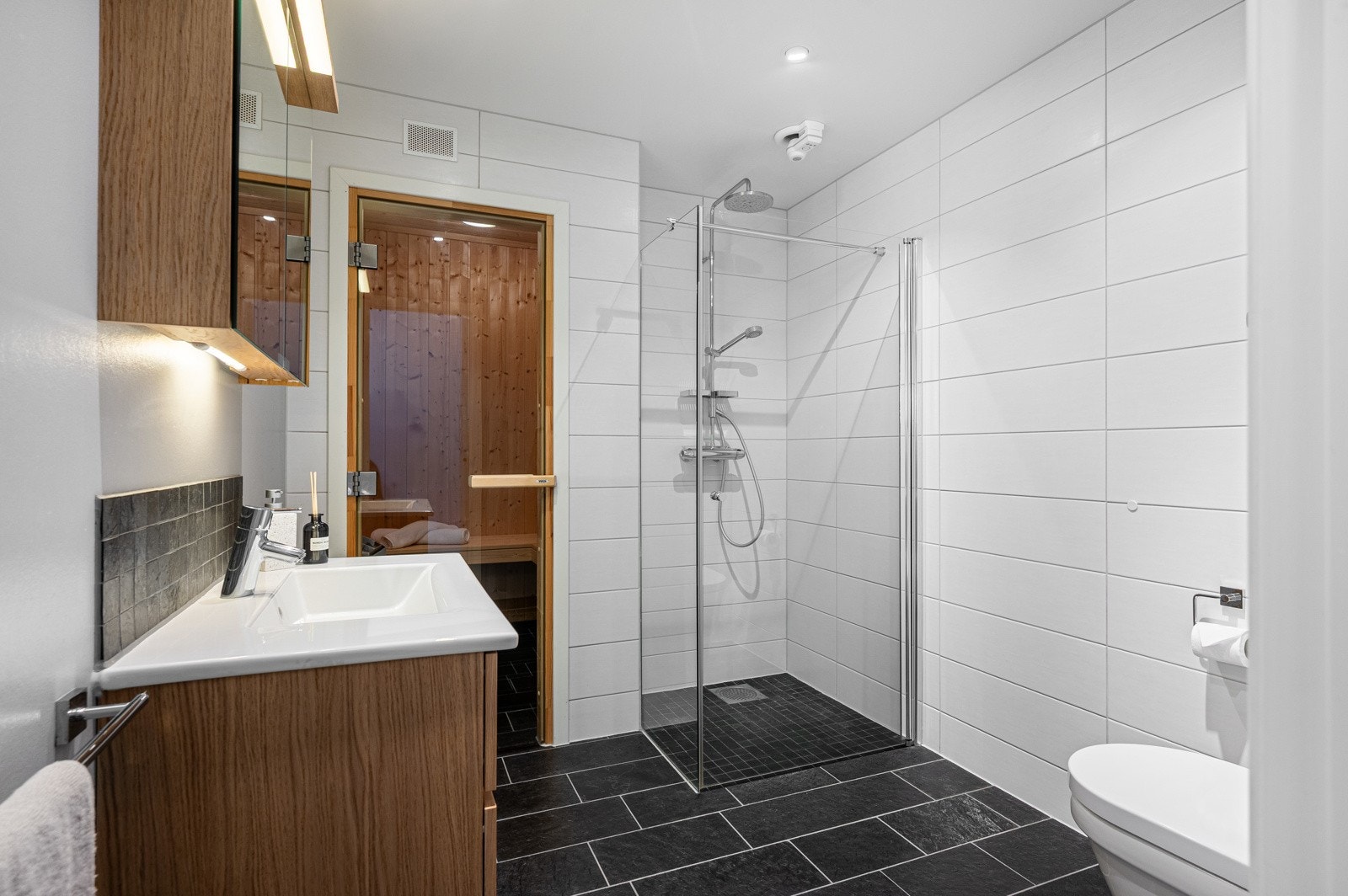 Stilrent helfliset bad med moderne innredning, romslig dusjhjørne og badstue. Galleribilde