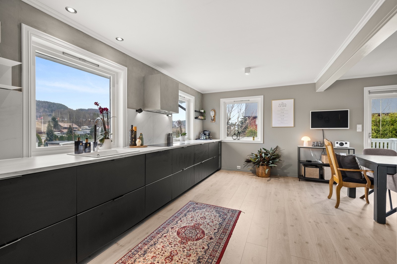 Kjøkkenet har en stilren innredning med mørke, glatte fronter med innfelte håndtak og laminat benkeplate med mye arbeidsplass. Galleribilde