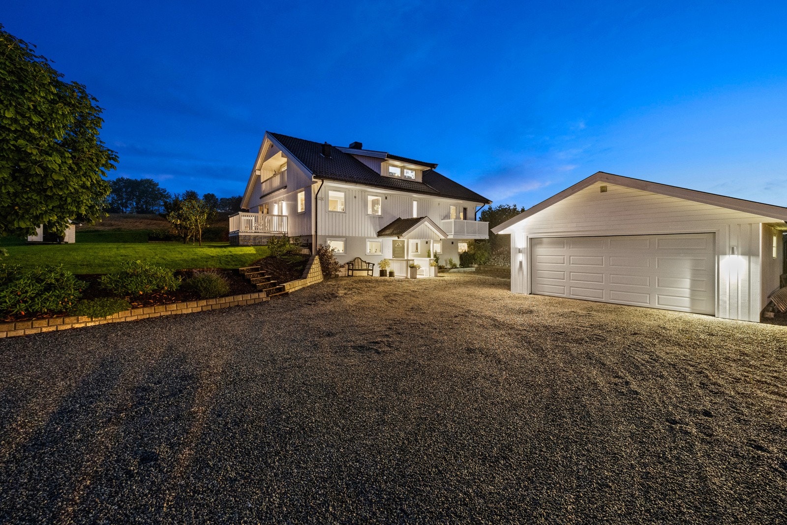 Stor, gruset gårdsplass med frittliggende dobbelgarasje. Galleribilde