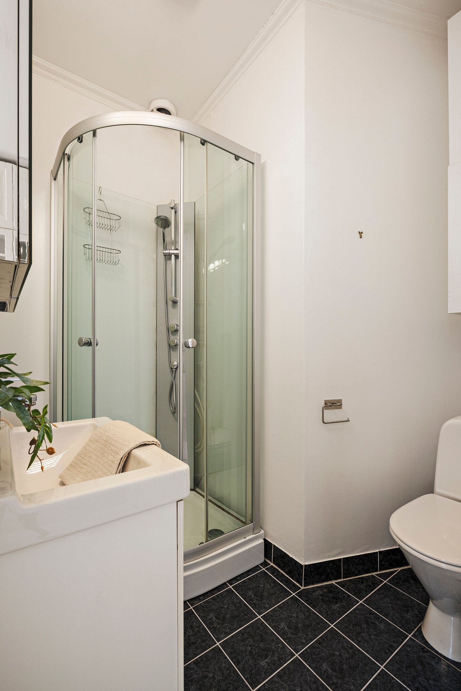 Badet består av toalett, dusjkabinett og servant med oppbevaring. Galleribilde