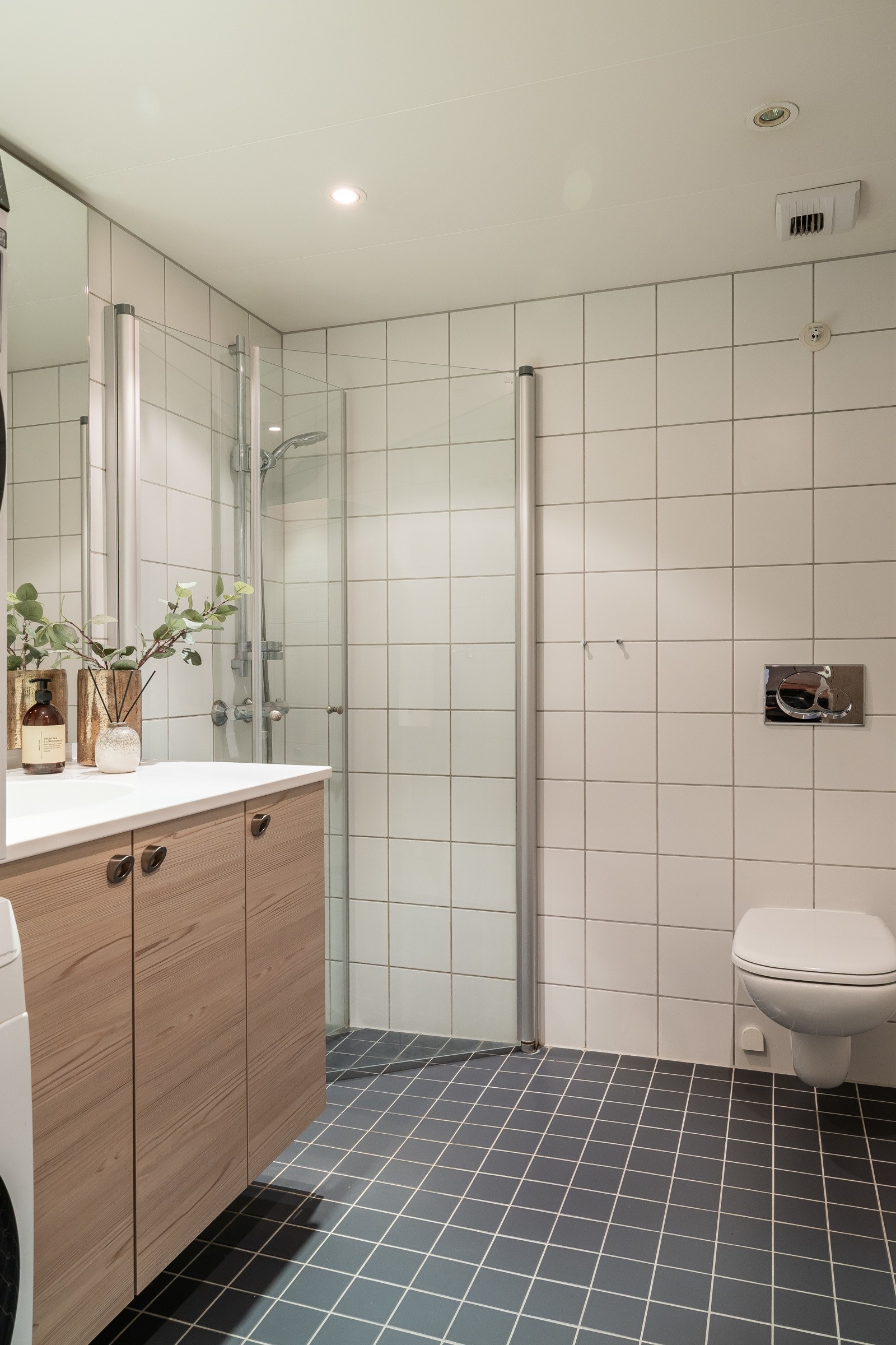 Praktisk baderom med innfelte lys, gulvvarme og vegghengt toalett, samt opplegg for vaskemaskin og tørketrommel Galleribilde