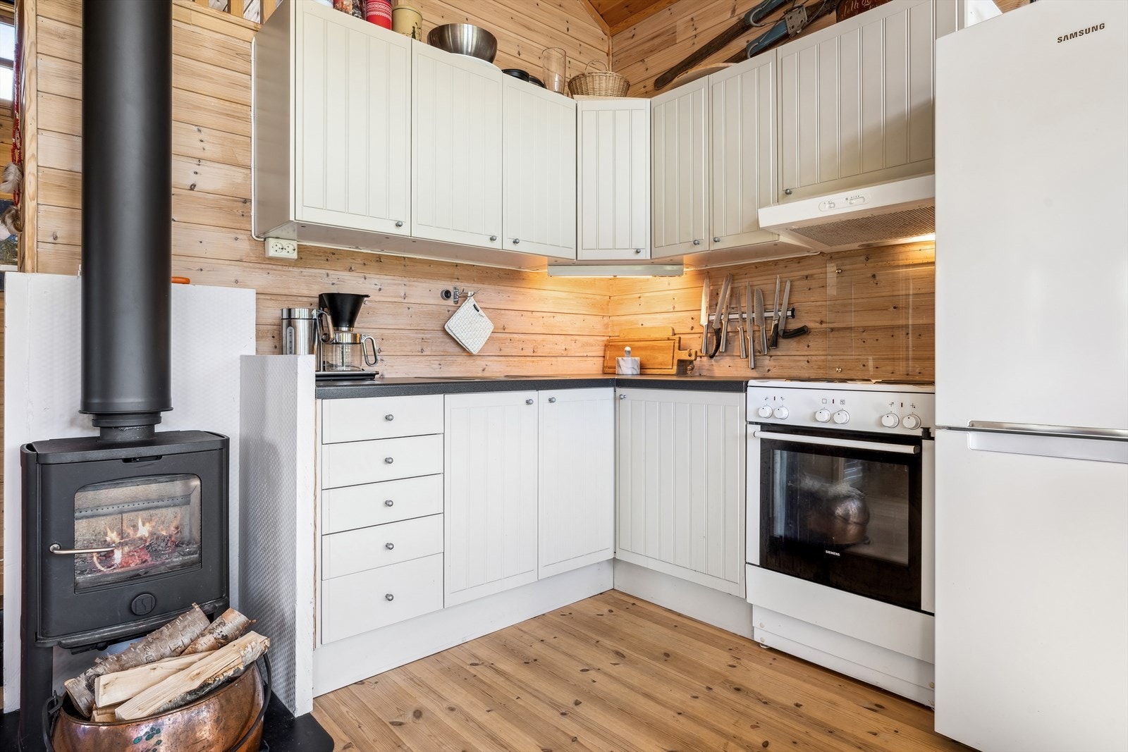 Kjøkkenet er stilrent med lyse profilerte fronter og benkeplate i laminat med nedfelt kjøkkenvask - Hvitevarene medfølger og består av komfyr og kombiskap kjøl/frys Galleribilde