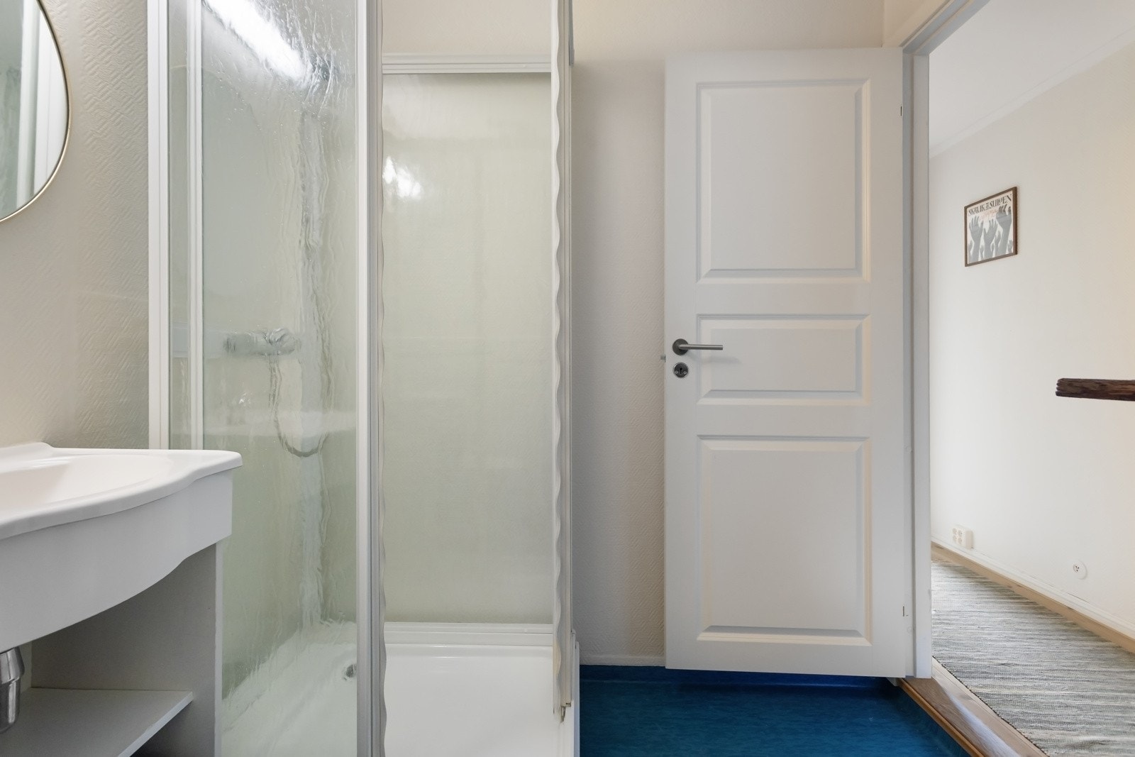 Badet er utstyrt med dusjkabinett, servant og toalett. Vinylbelegg på gulv Galleribilde