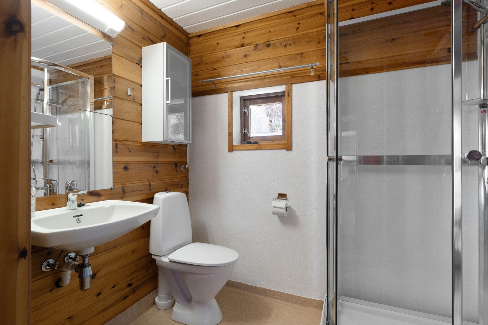 Badet er innredet med dusjkabinett, klosett, skapløsninger og servant. Galleribilde