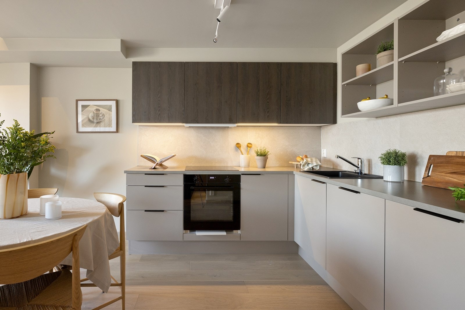 Kjøkkenet har et stilig uttrykk med en kombinasjon av benkeskap, overskap og vegghengte hyller som sikrer optimal plassutnyttelse. Galleribilde