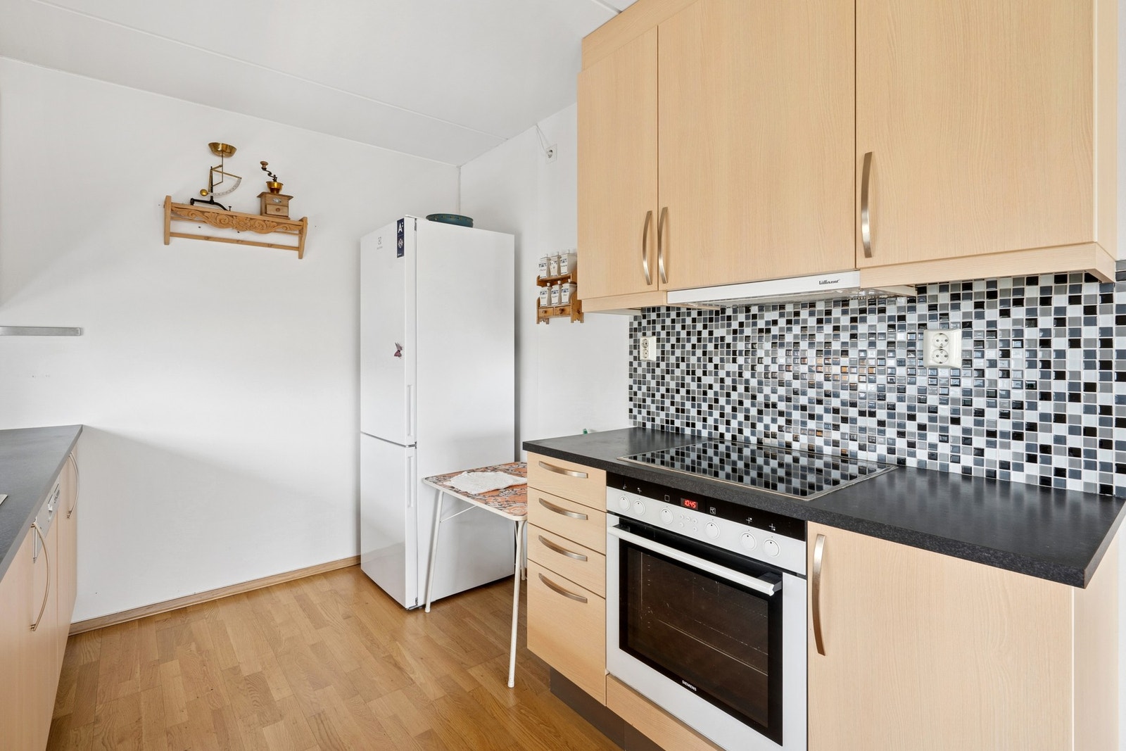 Kjøkken med åpen løsning mot stue. Innredning fra byggeår med slette fronter og benkeplater av laminat. Galleribilde