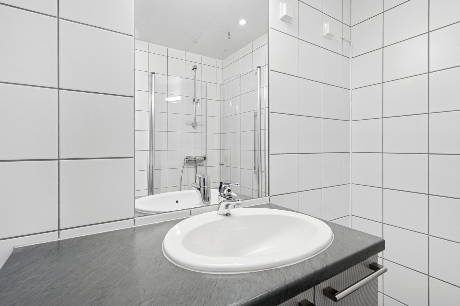 Dusj med innfellbare glassdører, servant med god oppbevaringsplass og et praktisk speilskap. Downlights skaper god belysning. Galleribilde