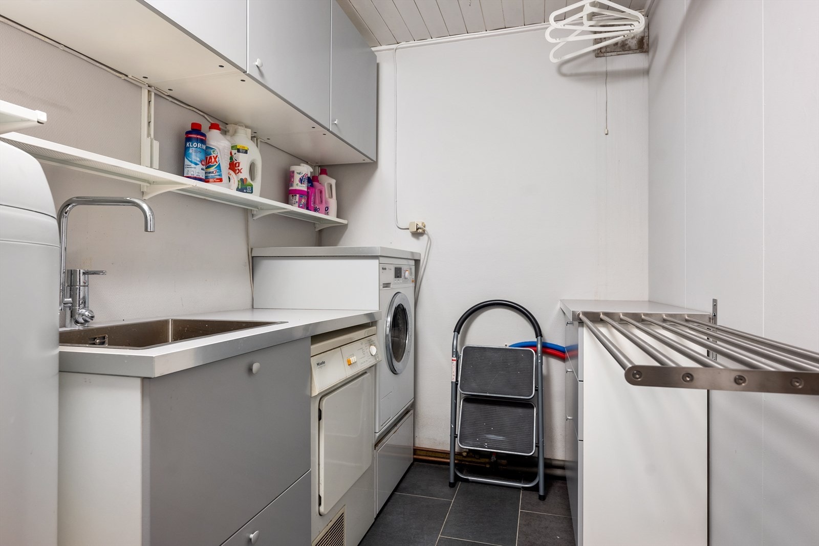 Vaskerom med opplegg for vaskemaskin og tørketrommel, pusset opp i 2016. Innredning med metallservant nedfelt i laminat benkeplate, med to skuffer under vasken. Her er også varmtvannstank og stoppekran. Galleribilde