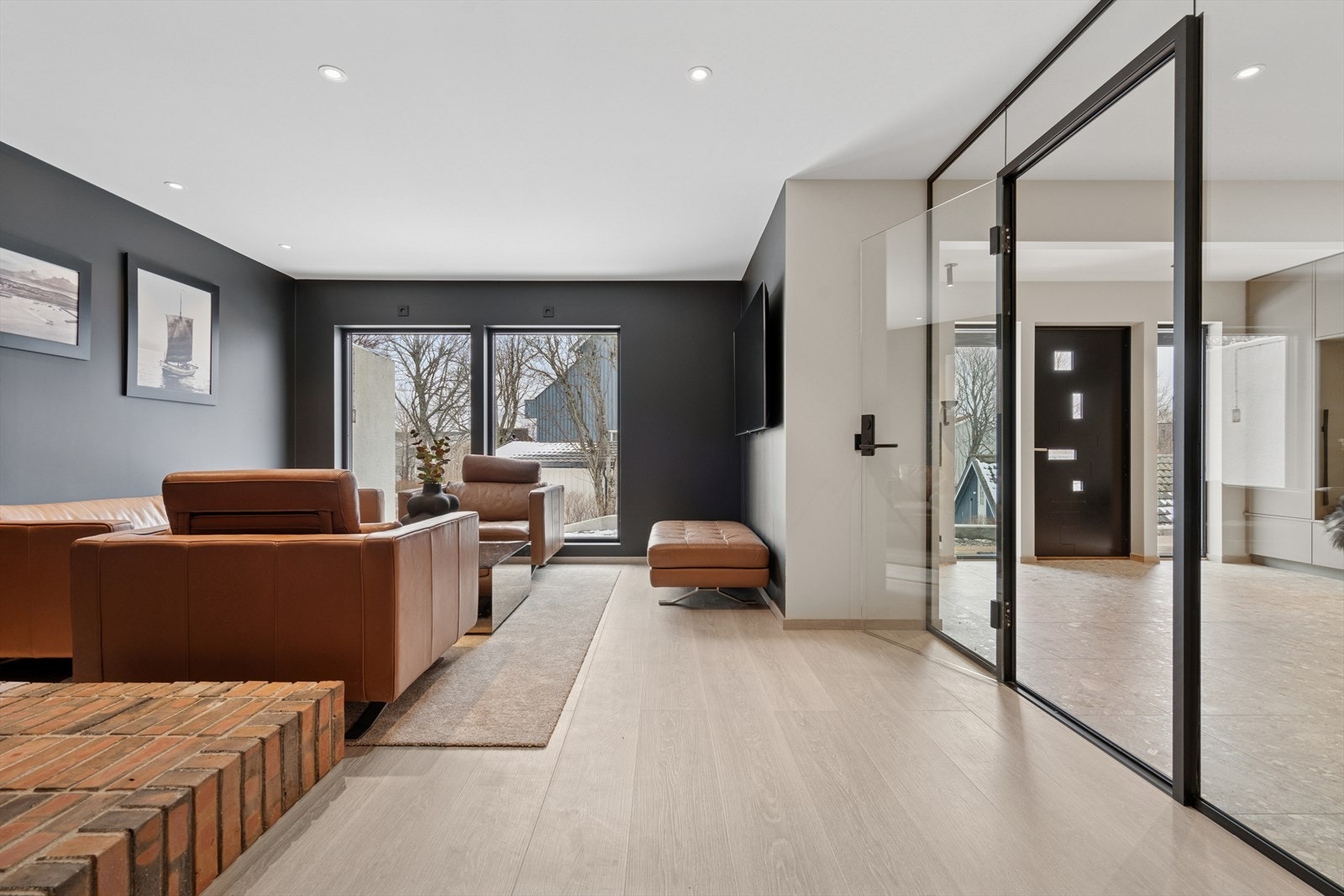 Det er glassvegg mellom hallen og peisstuen som skaper en åpen og luftig atmosfære Galleribilde