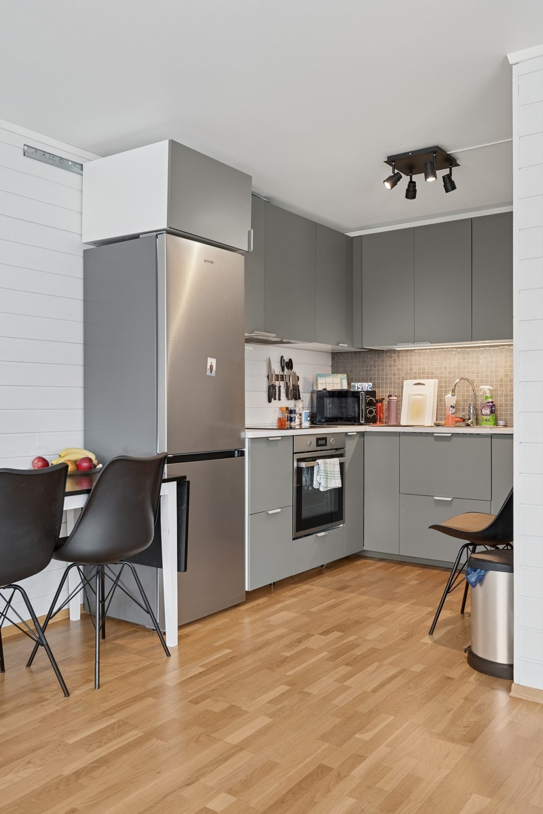 HYBEL: Kjøkkenet har innredning med slette malte fronter, laminert benkeplate og fliser på vegg over benk - Integrert koketopp, stekeovn og oppvaskmaskin Galleribilde