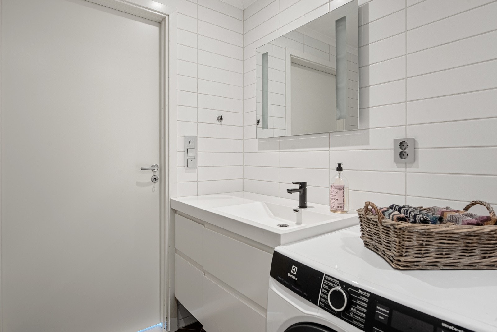 Badet har videre opplegg for vaskemaskin, hvit skuffeseksjon, heldekkende servant og et speil med integrert belysning. Galleribilde