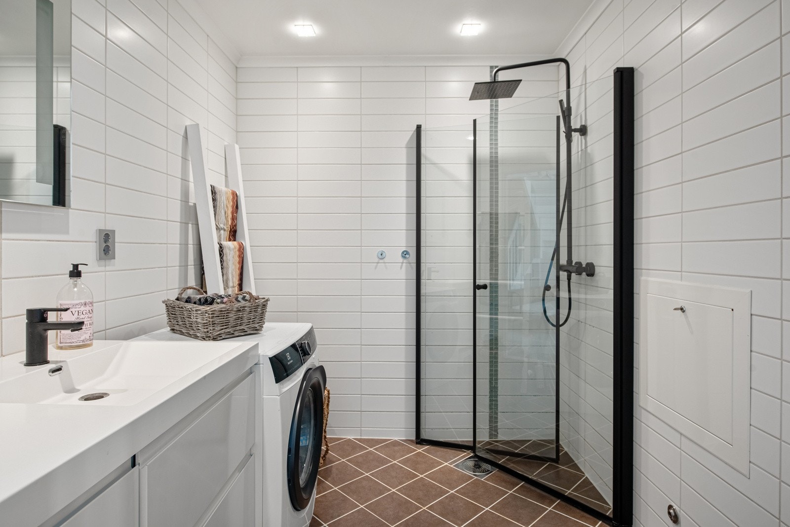 Boligen har ett bad i hver etasje. Badet i første etasje har dør inn fra stuen og har pene overflater med hvite fliser på veggene og jordfargede fliser over gulvvarme. I dusjhjørnet er det sort dusjgarnityr med hånddusj og regndusj. Galleribilde