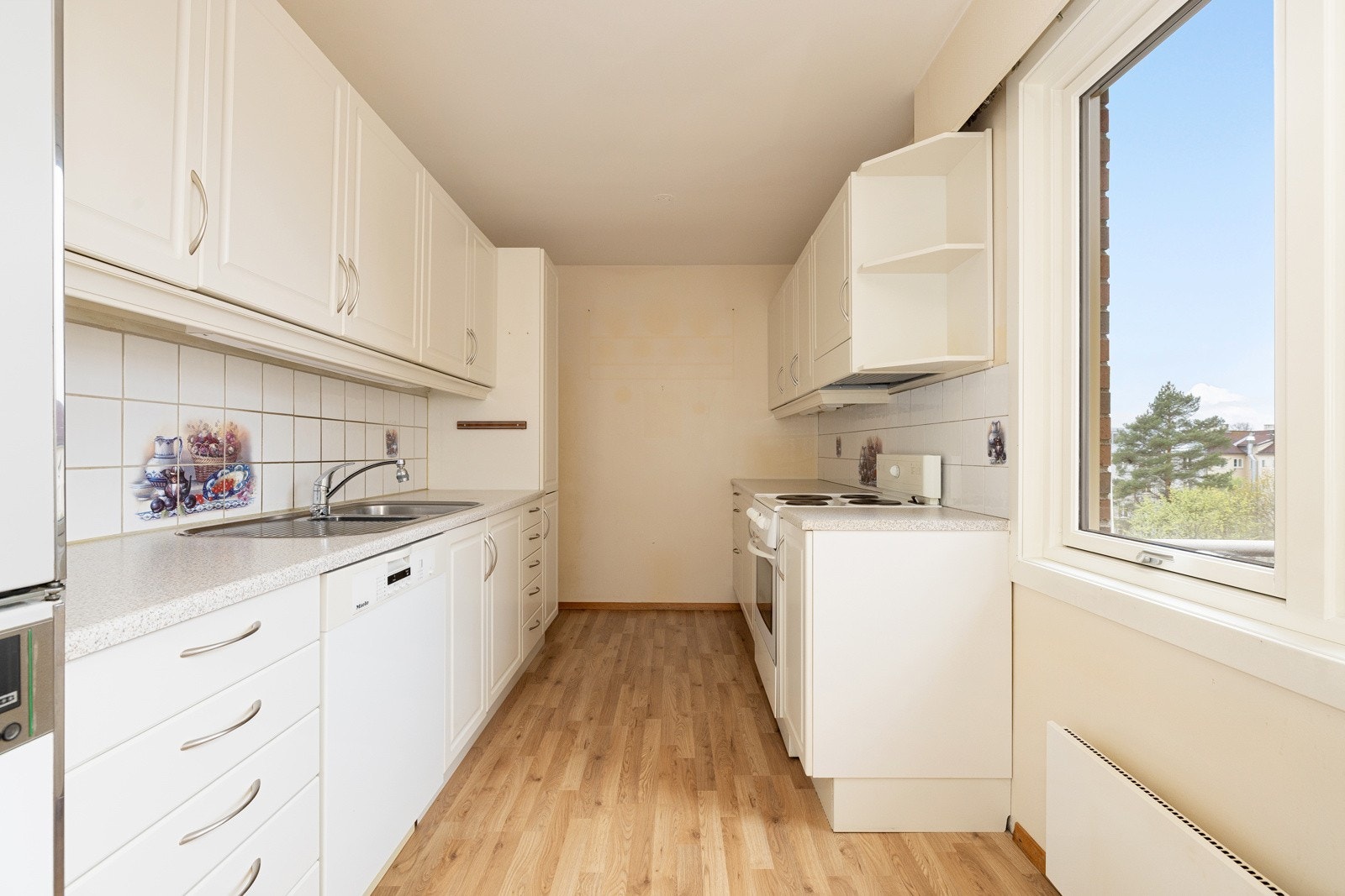 Fliser i benkeryggen og belysning under overskapene. Kjøkkenet er utstyrt med oppvaskmaskin, komfyr og vegghengt ventilator. Galleribilde