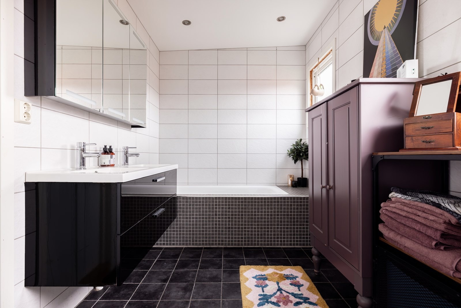 Pent og meget romslig flislagt bad fra 2011 med varmekabler i gulvet og innfliset badekar. Her er det god oppbevaringsplass i speilskap samt i skuffeinnredning under de doble servantene. Det er i tillegg mulighet for å sette inn ytterligere møblement. Galleribilde