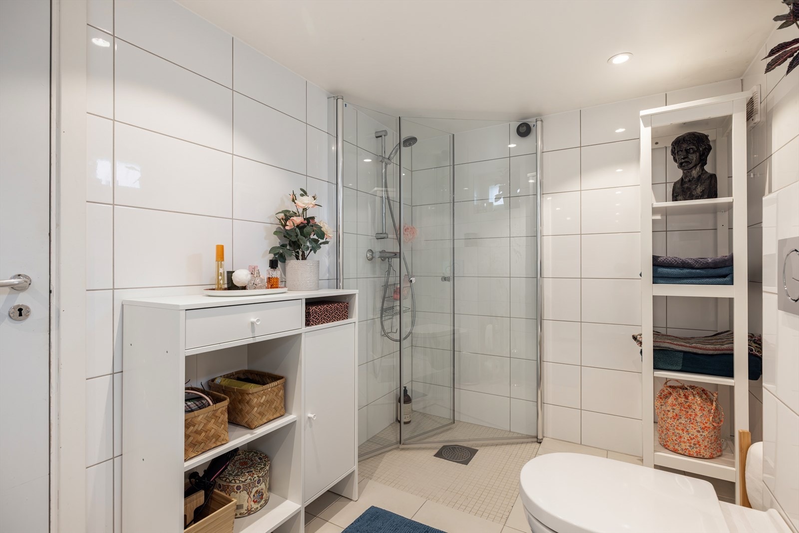 I dette badet er det dusjhjørne med innfellbare dusjdører i herdet glass. Her er det lagt fliser på vegger og gulv med varmekabel under gulvflisene. Downlights i himling samt naturlig lys fra vindu gir gode lysforhold i rommet. Galleribilde