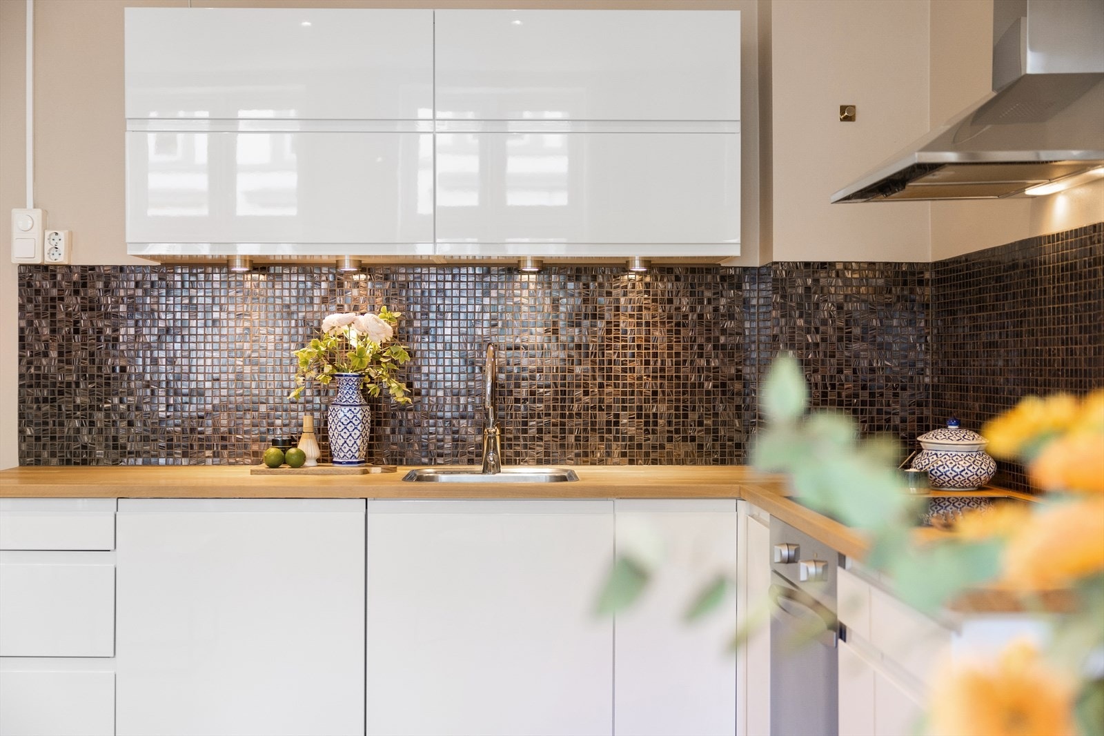 Innredningen har hvite, glatte fronter, heltre benkeplate og nedfelt oppvaskkum med ettgreps, svingbart blandebatteri. Praktisk kombinasjon av over- og underskap, med belysning under overskap og dekorative mosaikkfliser mellom benk og overskap. Galleribilde