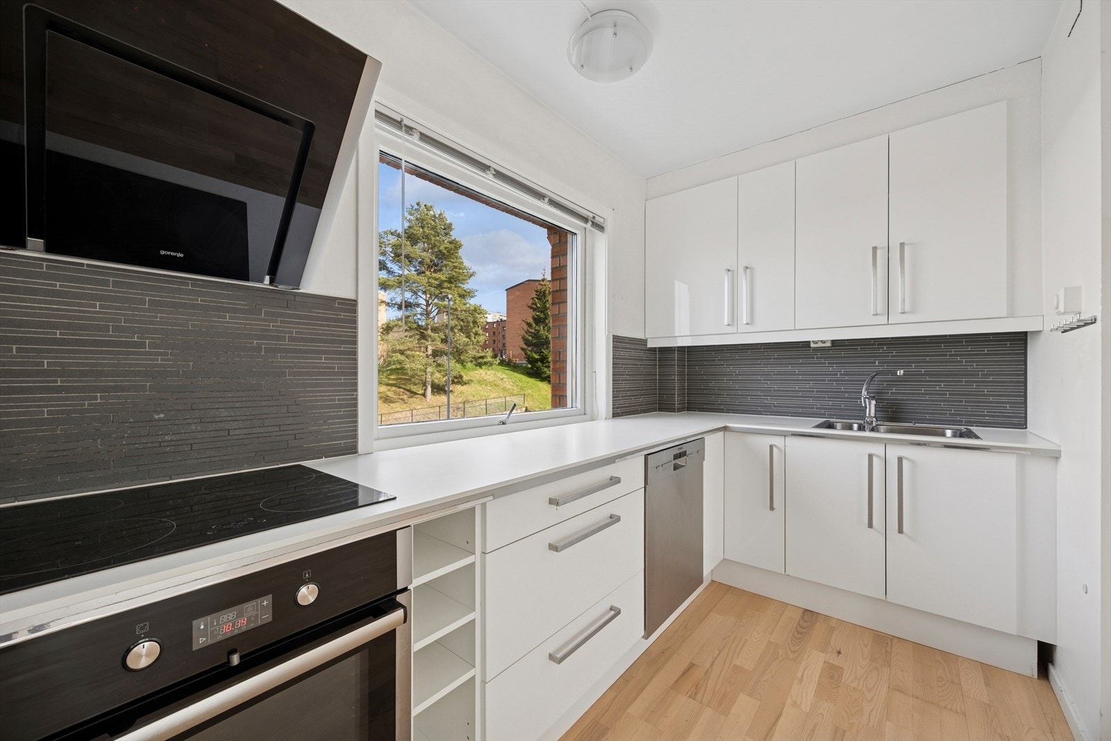 Kjøkkenventilator med kullfilter sørger for effektiv ventilasjon og et friskere inneklima. Her nyter man flotte grønne omgivelser utenfor, via det fine vinduet på kjøkkenet. Høyt, fritt og usjenert! Galleribilde