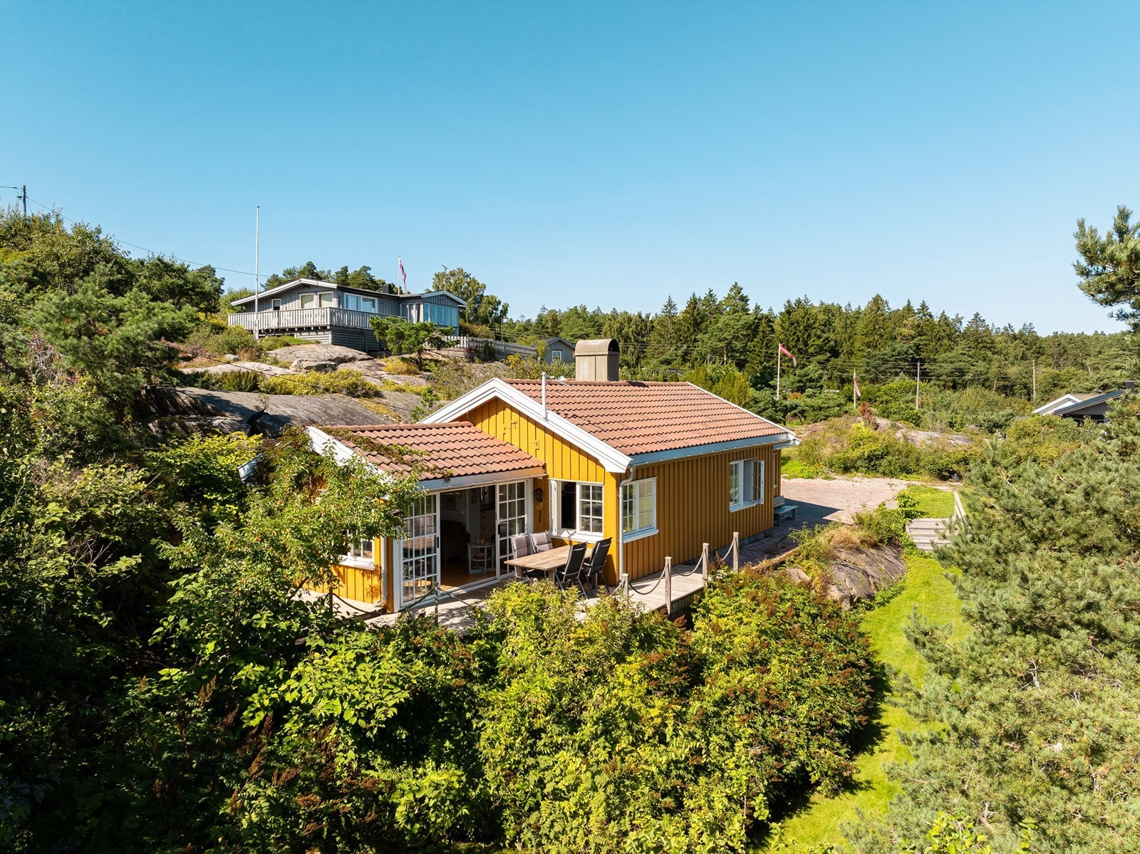 Av så vel naturlig vegetasjon som plantede prydbusker får eiendommen et grønt og frodig preg i årets varme måneder. Galleribilde