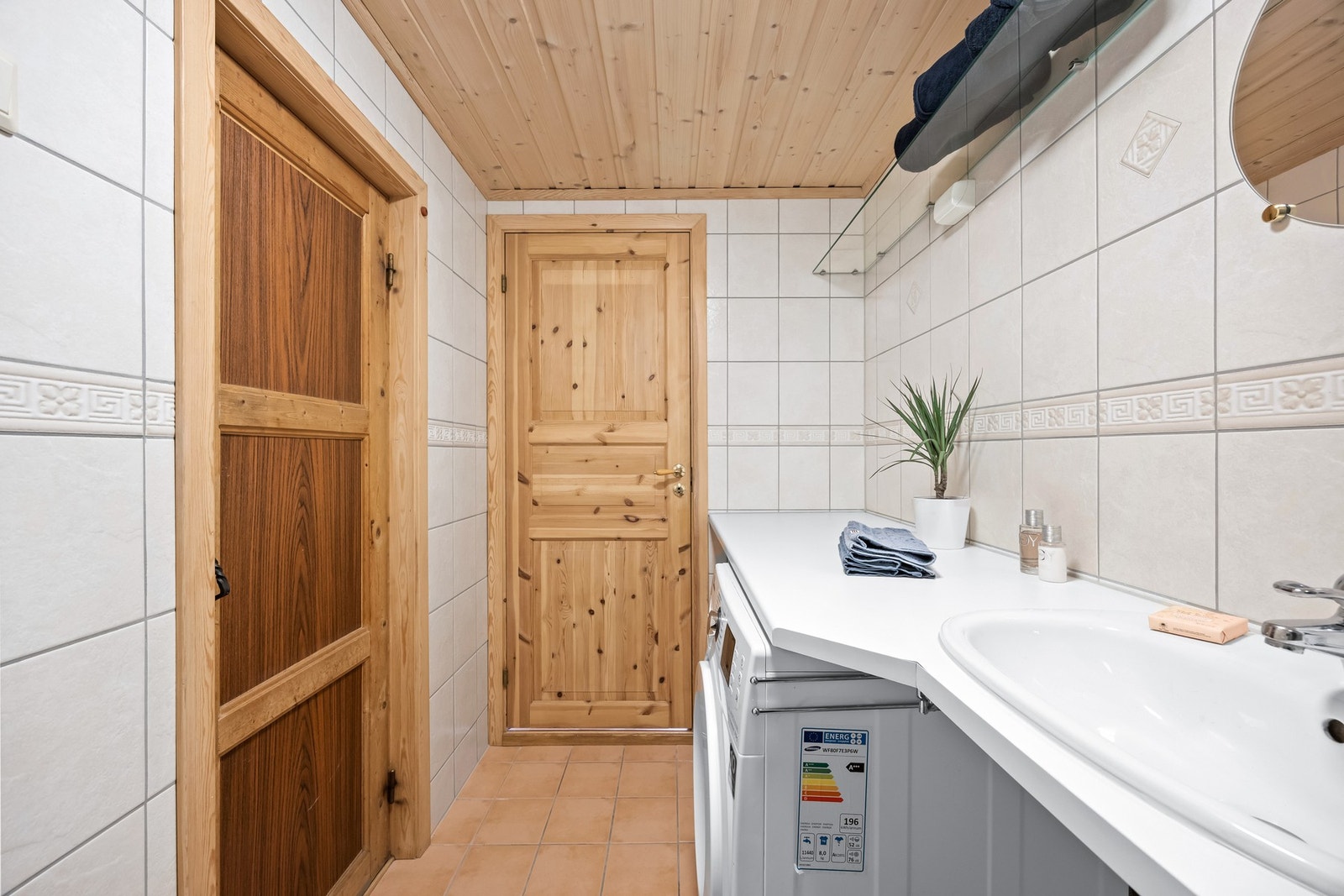 Dette badet har opplegg for vaskemaskin og en benk med laminatoverflate og nedfelt vask som gir god arbeidsflate. Galleribilde