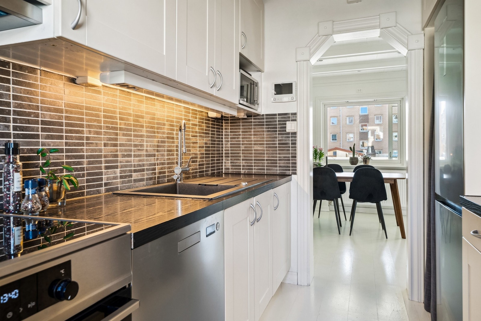 Pent kjøkken i adskilt løsning med god skap- og benkeplass. Innredning med lyse klassiske fronter. Benkeplate i laminat med nedfelt oppvaskkum i silgranitt (2018) Galleribilde