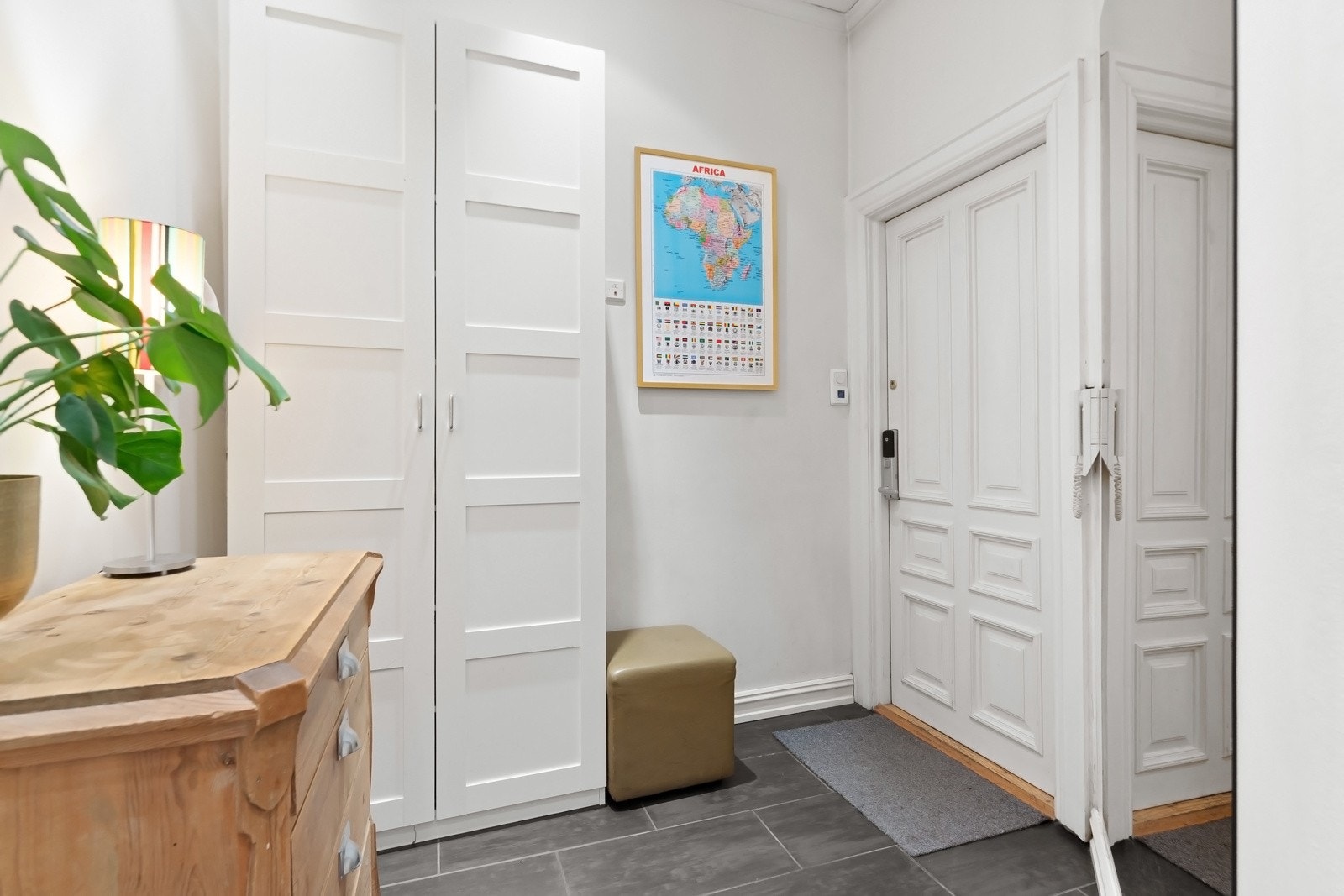 Entreen har grå fliser på gulv med gulvvarme, lysmalte veggflater, himling med downlights og et dobbelt garderobeskap. Galleribilde