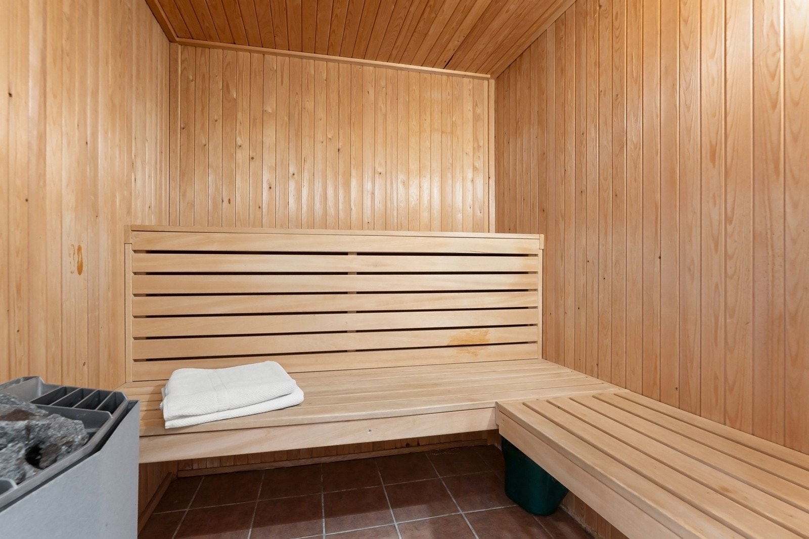 Badstuen har gulvfliser, panel på vegger og tak, plassbygd benk i tre og en badstueovn. Galleribilde