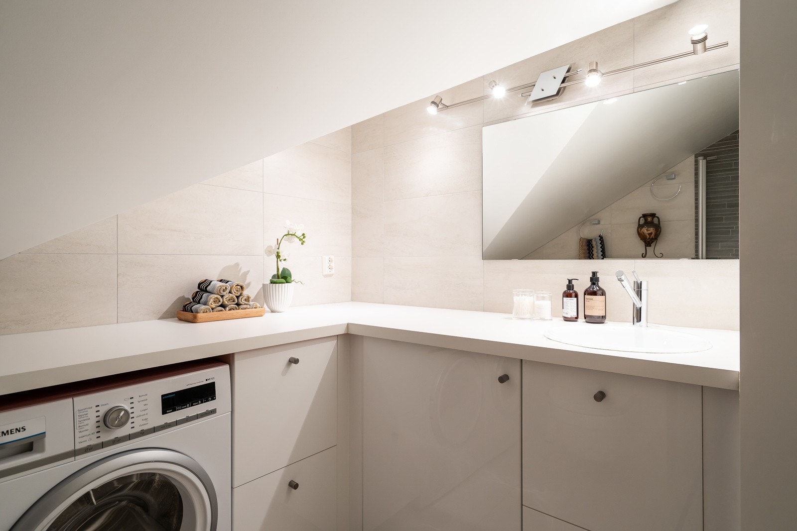 Dette badet brukes som bad/wc/vaskerom og har bl.a. vegghengt toalett, benkeinnredning med nedfelt servant, ettgreps servantarmatur samt opplegg og plass for vaskemaskin og tørketrommel. Galleribilde