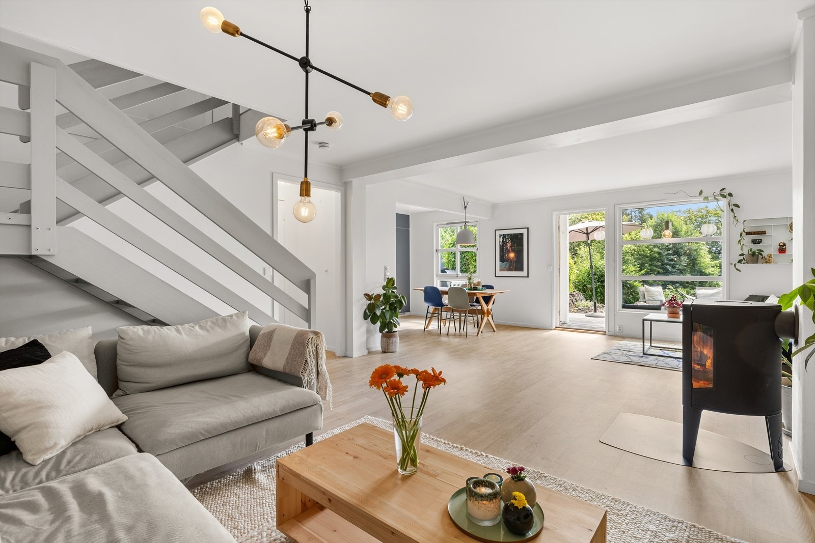 Stor og lys stue med peis, utgang til markterrasse og åpen løsning til kjøkken Galleribilde