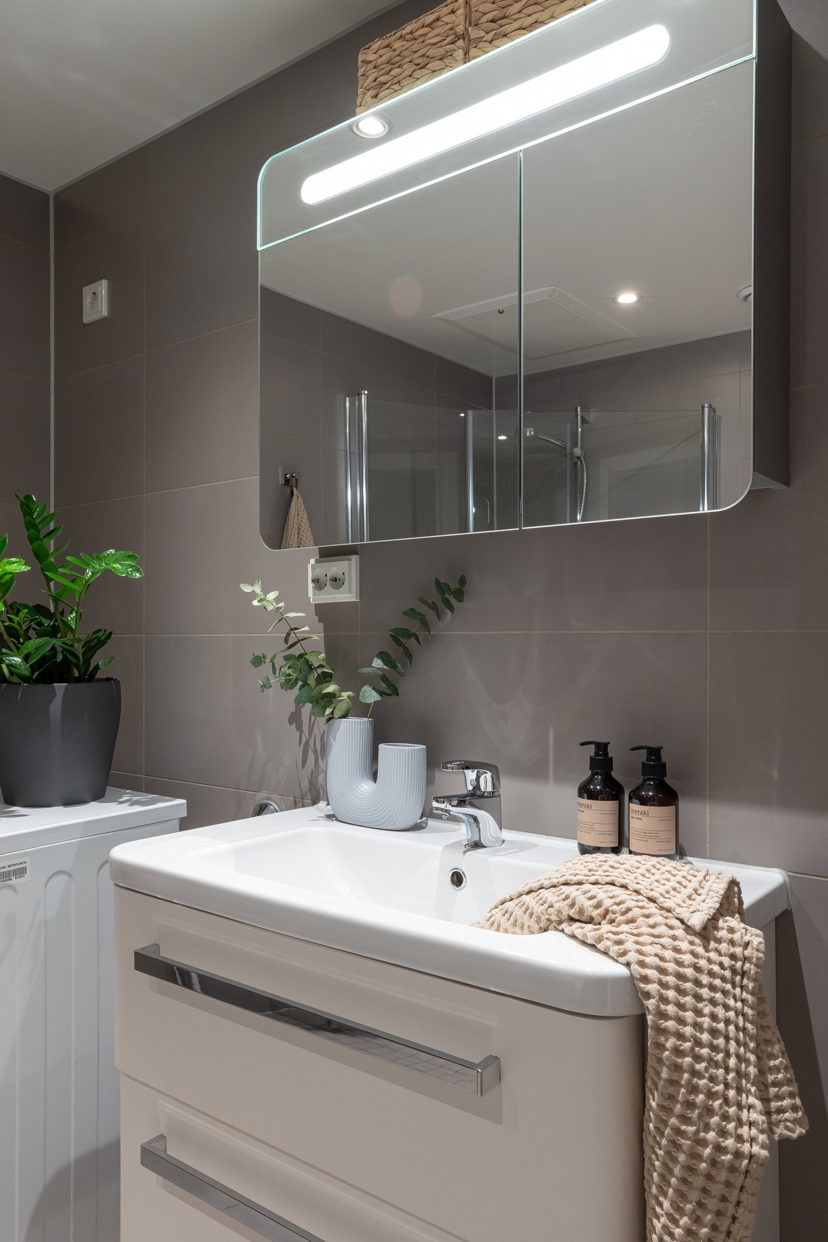 På badet er det vegghengt servant med oppbevaring, vegghengt speilskap med integrert belysning. Galleribilde