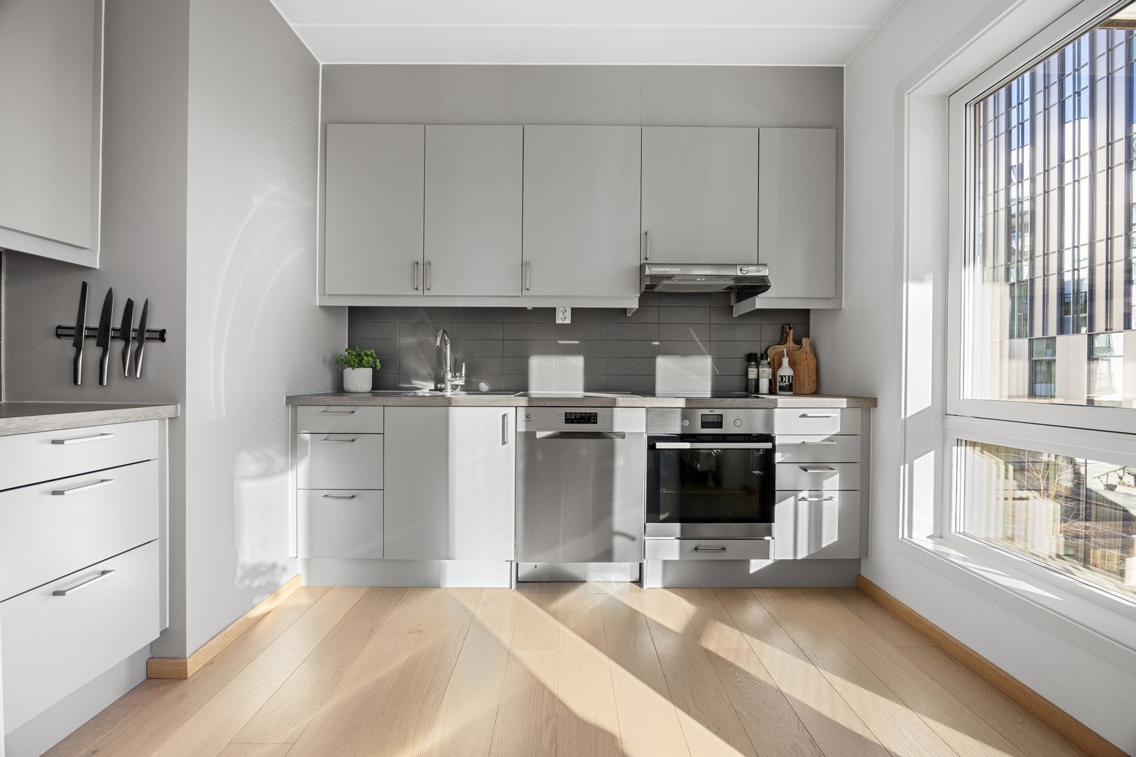 Det er lyse fronter, fliser over laminat benkeplate, i tillegg til benkeskapsbelysning og stikkontakt under overskap. Galleribilde